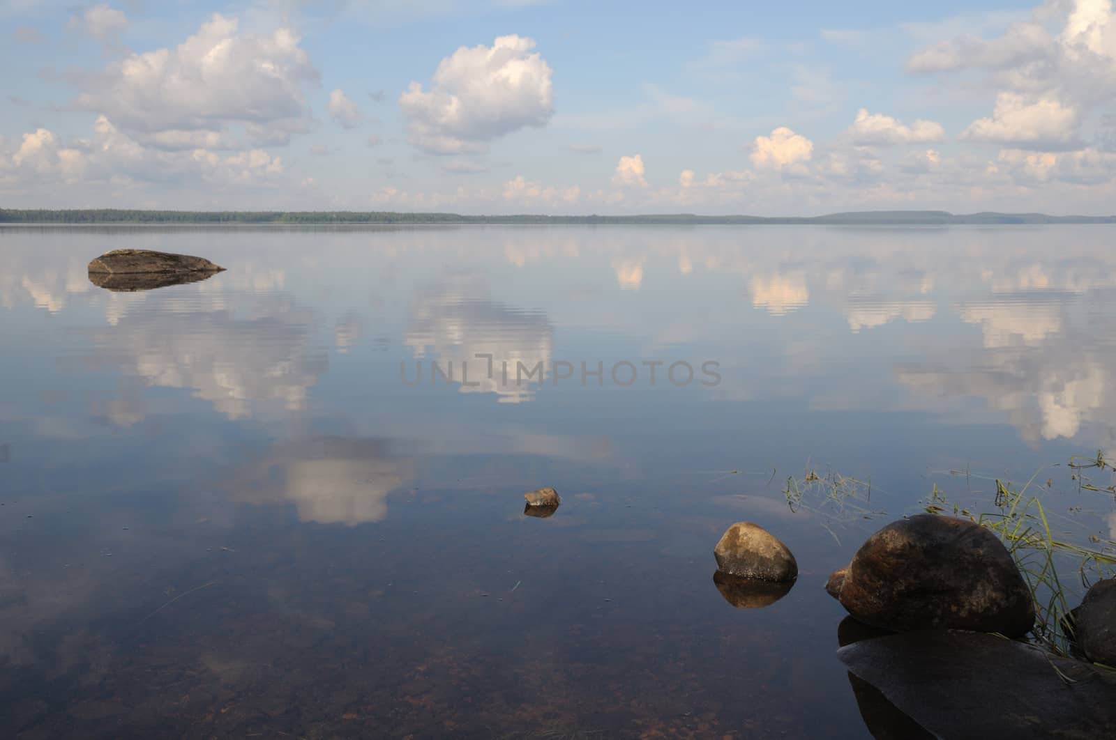 The bottom of the lake with a lot of stones and reflected sky