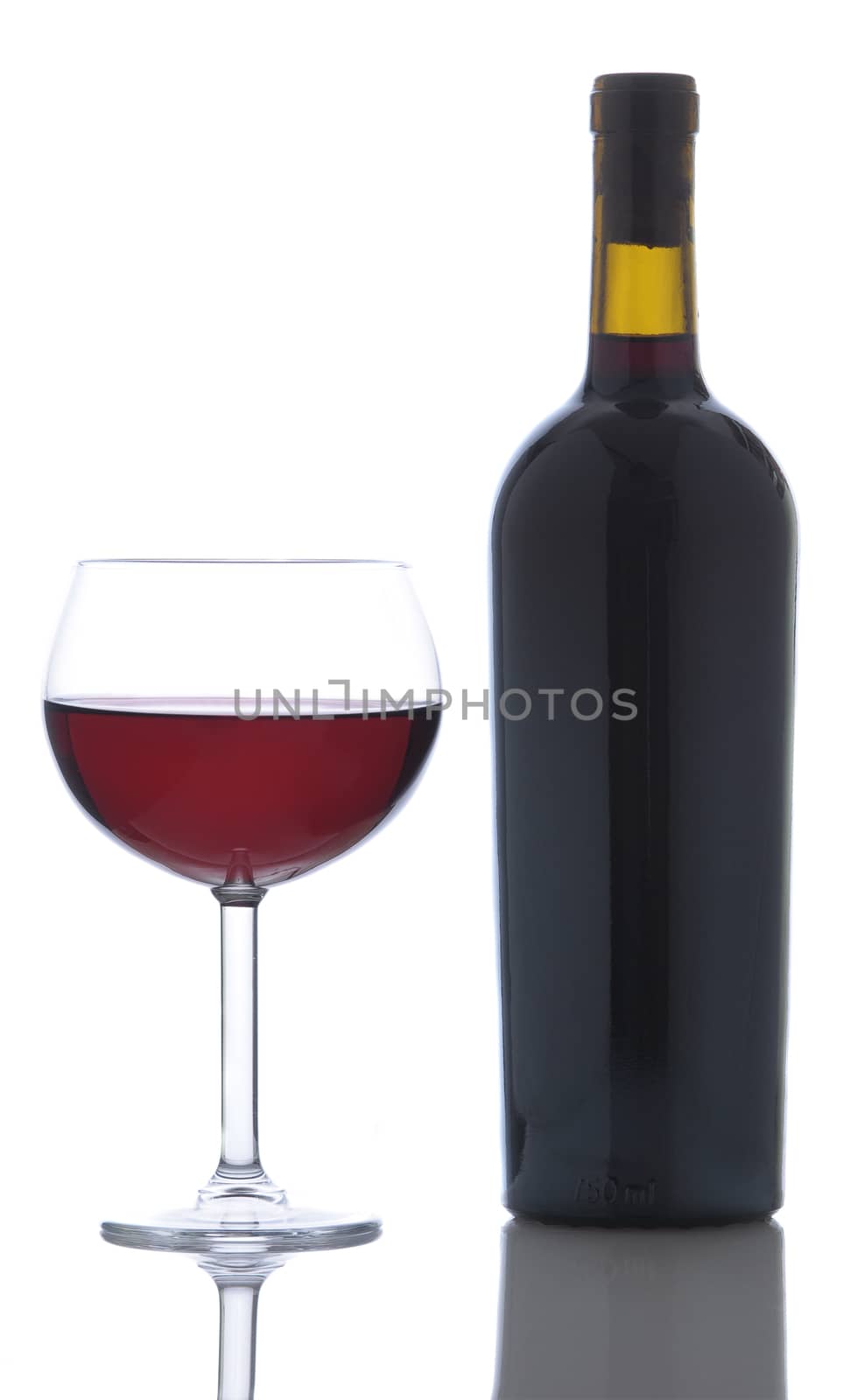 Glass of red wine next to a full bottle without label isolated on white vertical format