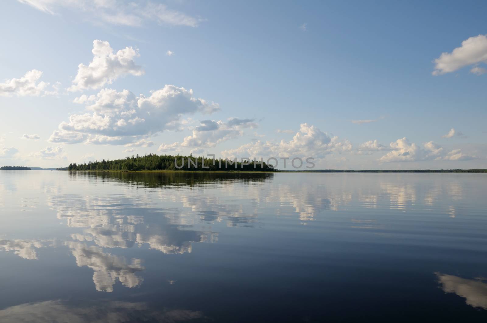 The beautiful picture of Karelian forest at the edge of a lake, and some huge boulder in this lake