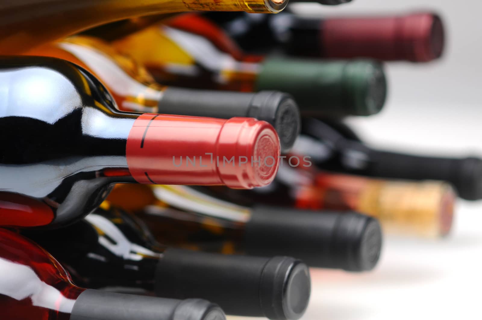 Closeup of several assorted wine bottles laying on their side. Horizontal format with selective focus.