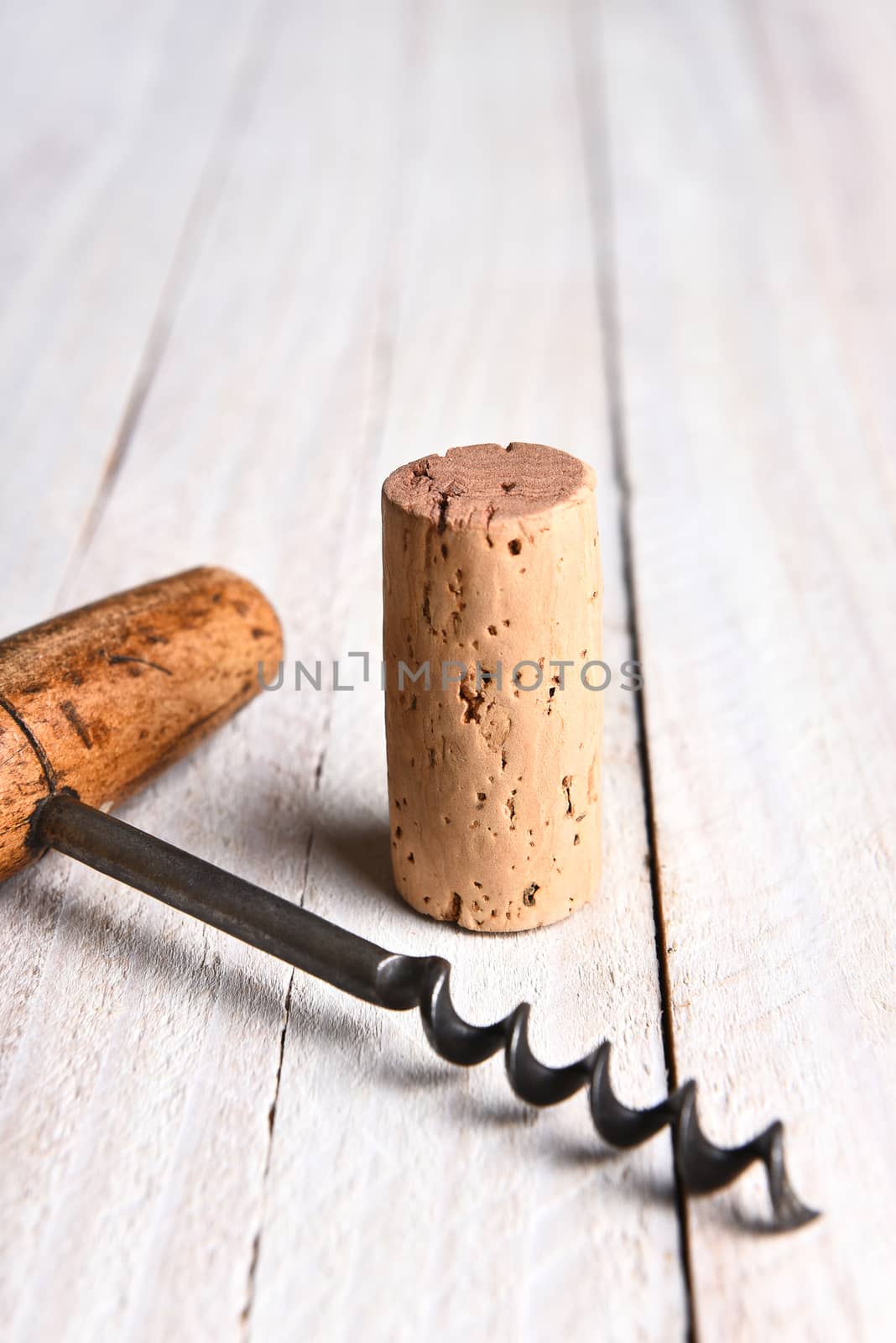 Still life closeup of a cork and corkscrew on a white wood table. Vertical format with copy space.