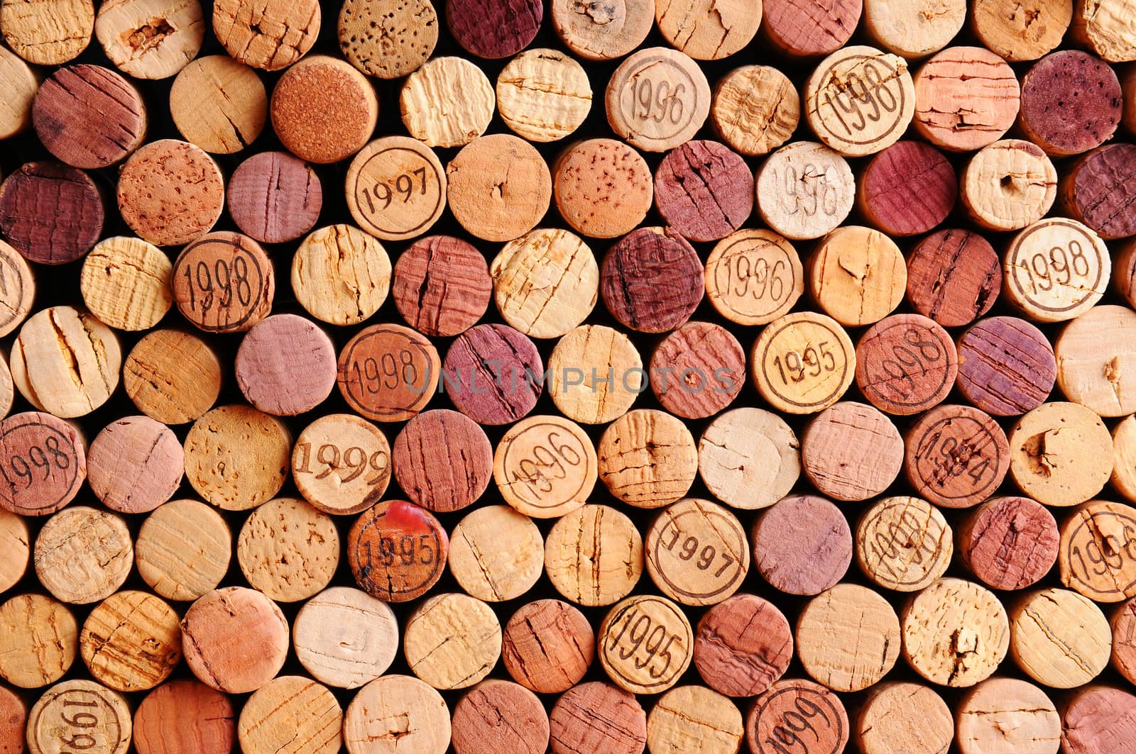 Closeup of a wall of used wine corks. A random selection of use wine corks, some with vintage years. Horizontal format that fills the frame.
