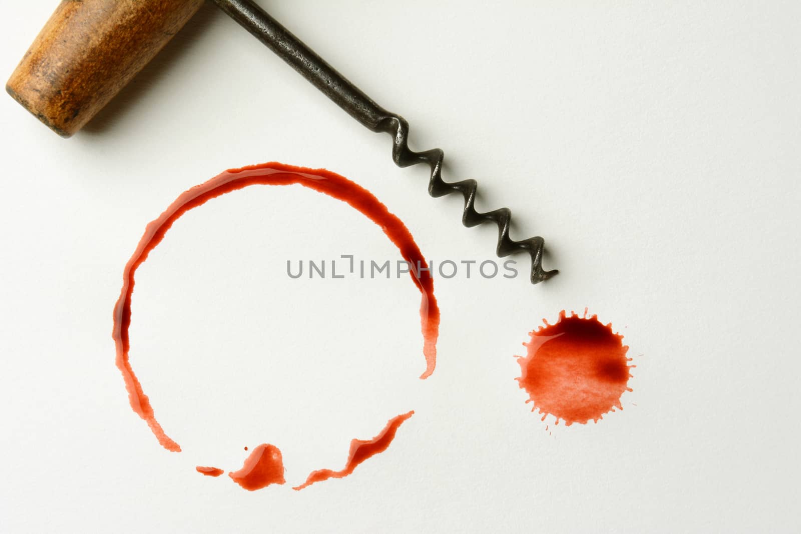 Wine stains cork and antique corkscrew on paper. Fills the frame, in horizontal format. The stains are from a bottle bottom and drips.