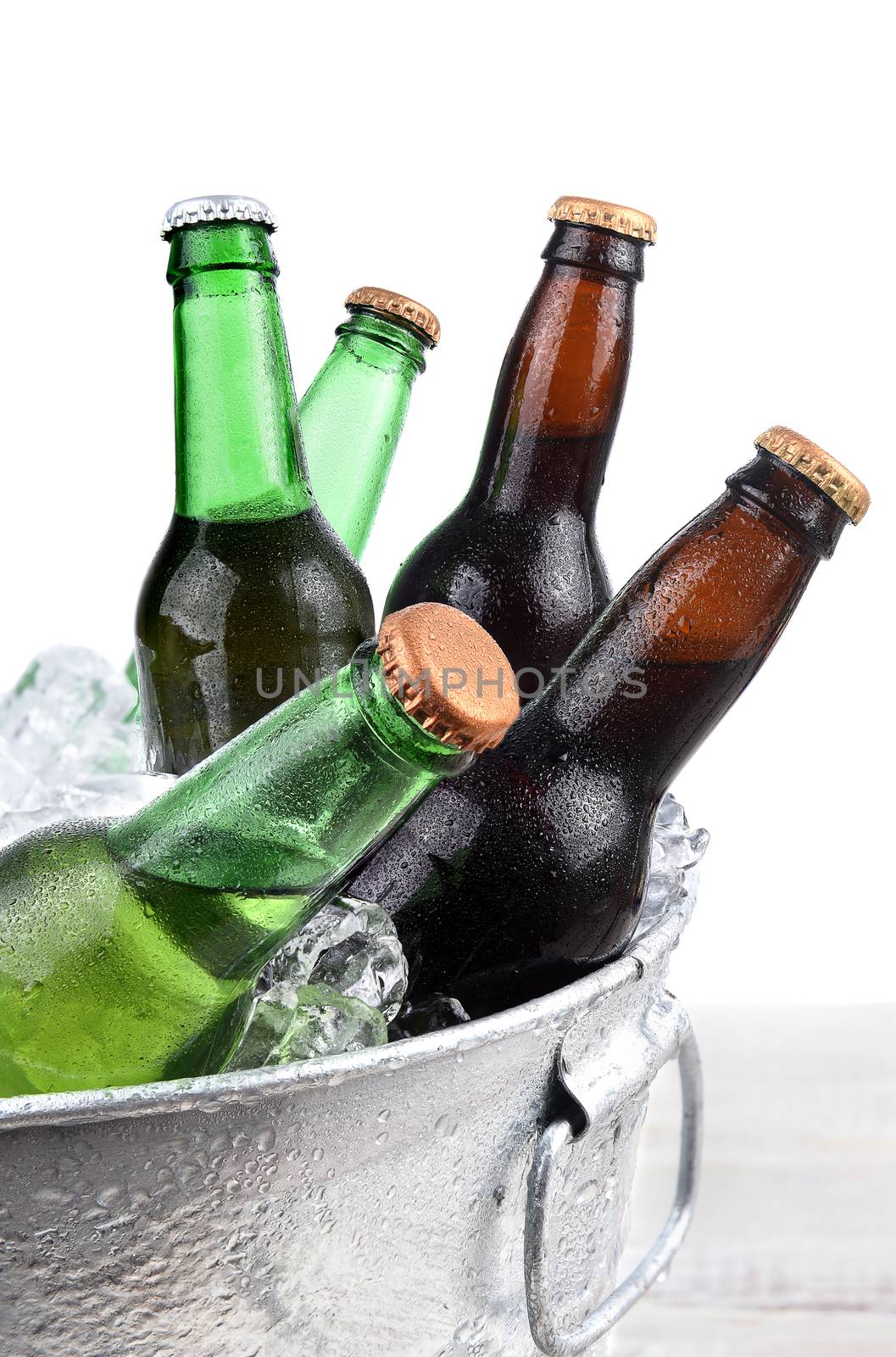Closeup of green and brown beer bottles in a metal ice bucket. 