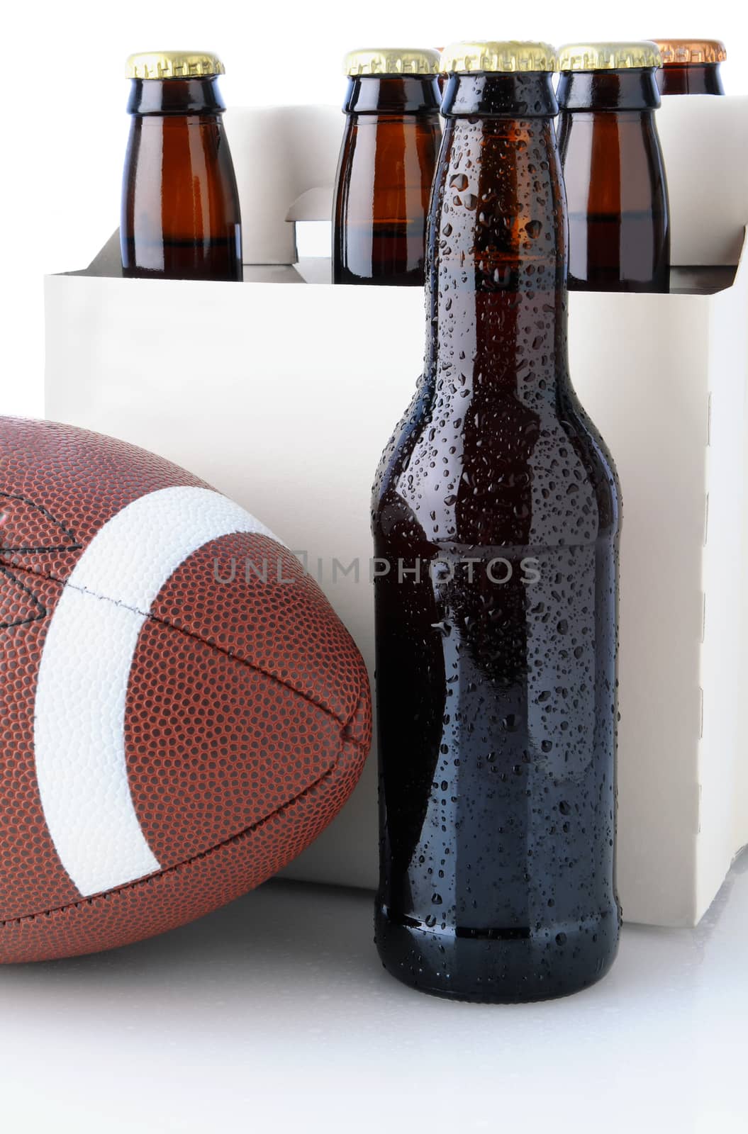 Six pack of beer with an American Football in front. Vertical format isolated on white with reflection.