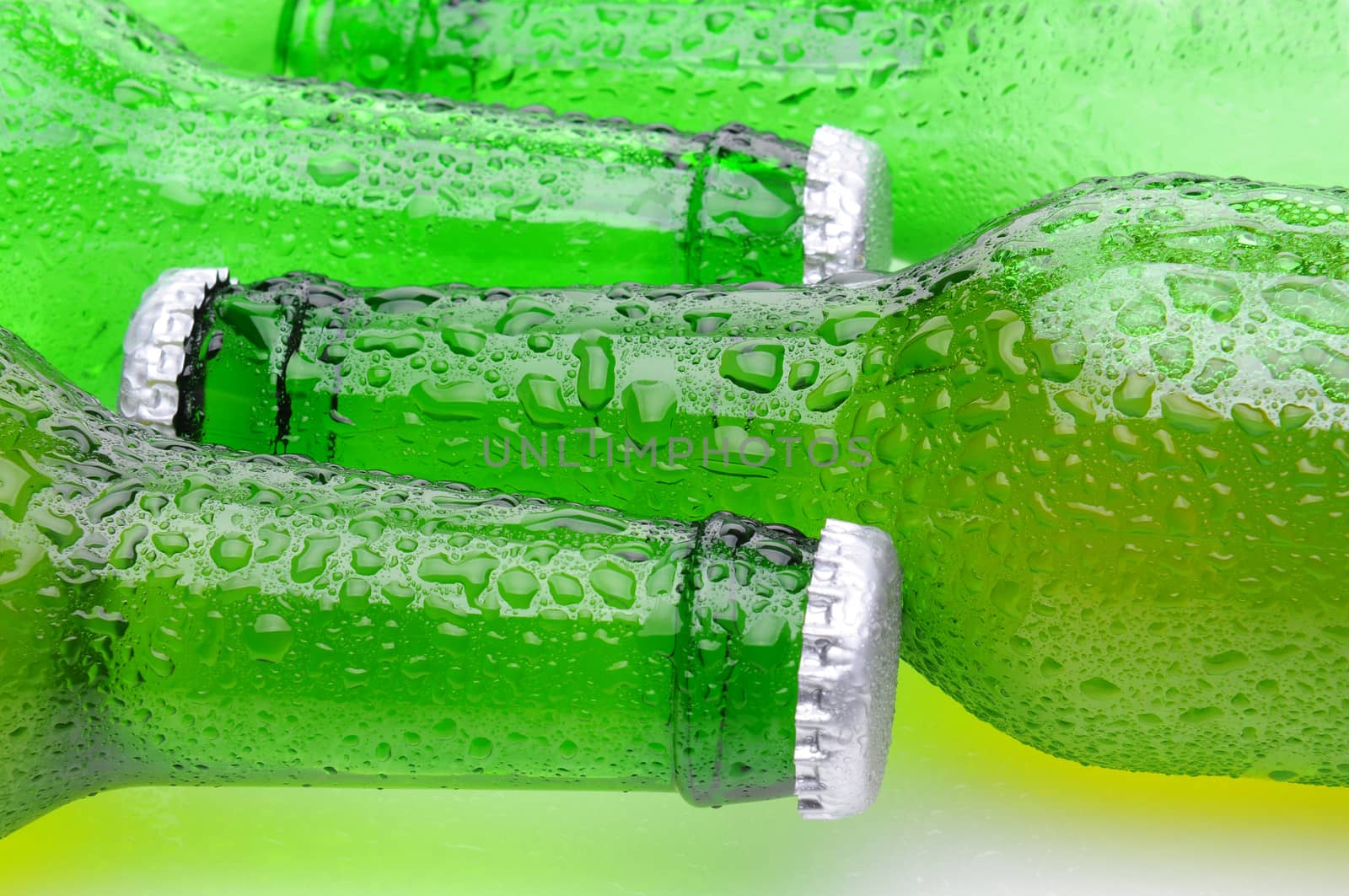 Closeup of green beer bottles laying on their side in horizontal format. Bottles are covered with condensation.