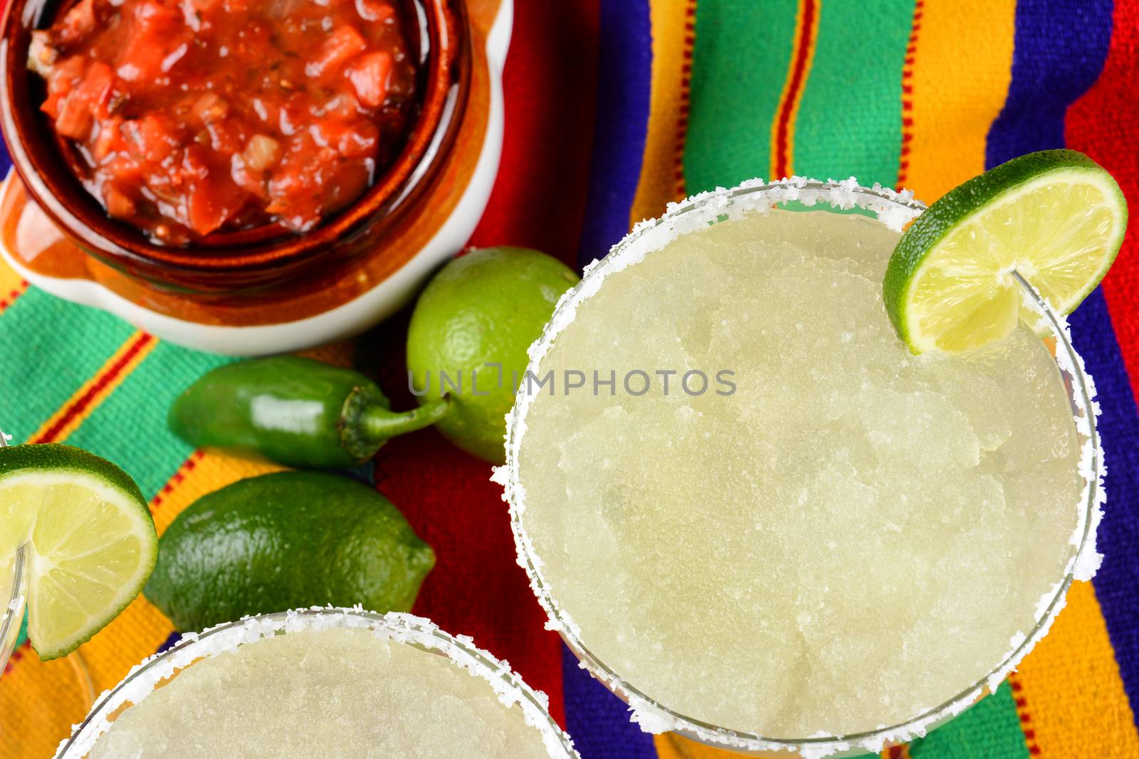 Margaritas and Salsa on a colorful  table cloth, with limes, and by sCukrov