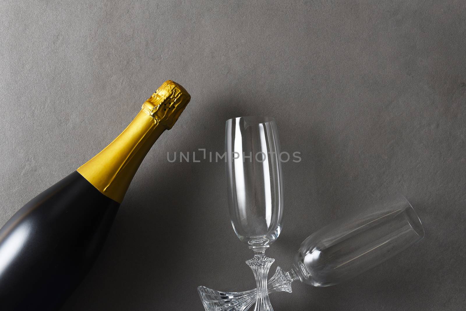 Flat lay Champagne and two glasses on a dark gray table with strong side light.