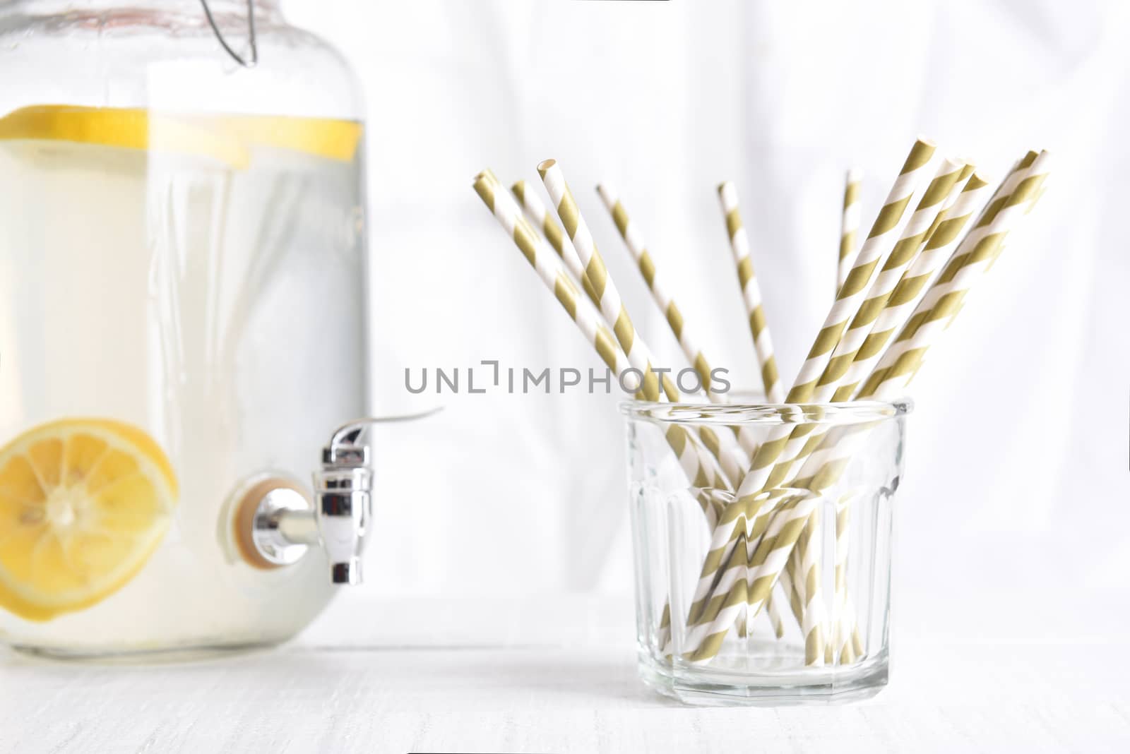 Lemonade pitcher with a glass of drinking straws by sCukrov