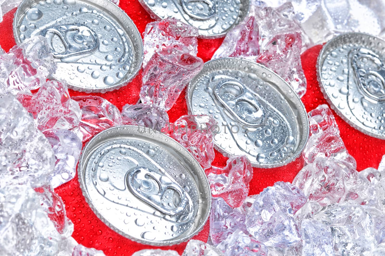 Closeup of a group of soda cans in ice with condensation.
