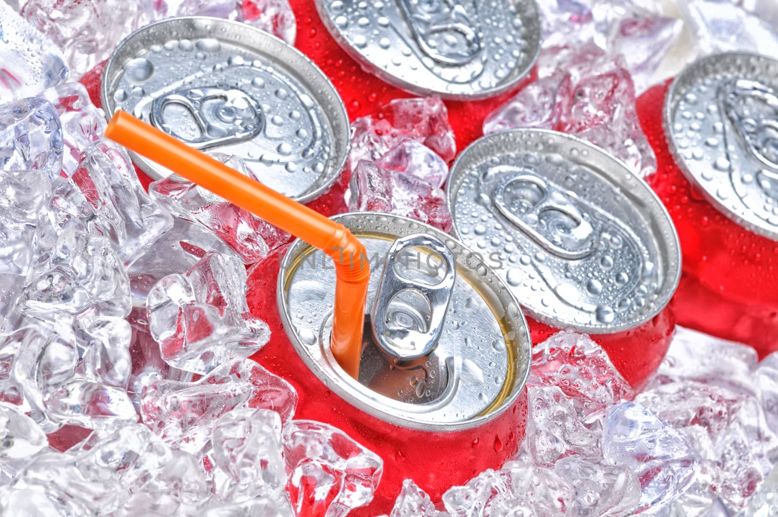Soda Cans in Ice with a drinking straw with condensation.