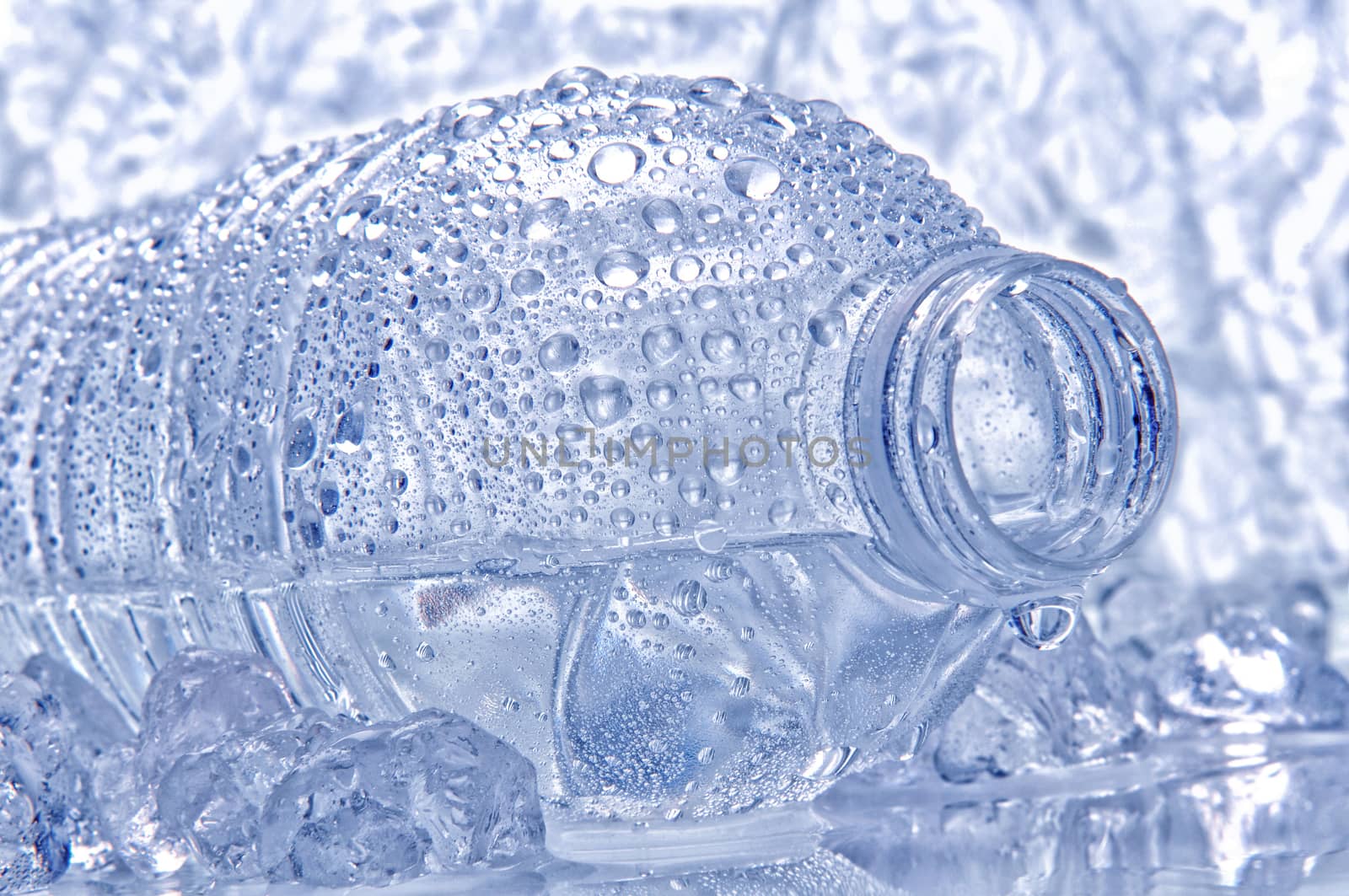 Water bottle laying on its side with droplets and drip coming out of the opening. Intentional cool tones and shallow depth of field.