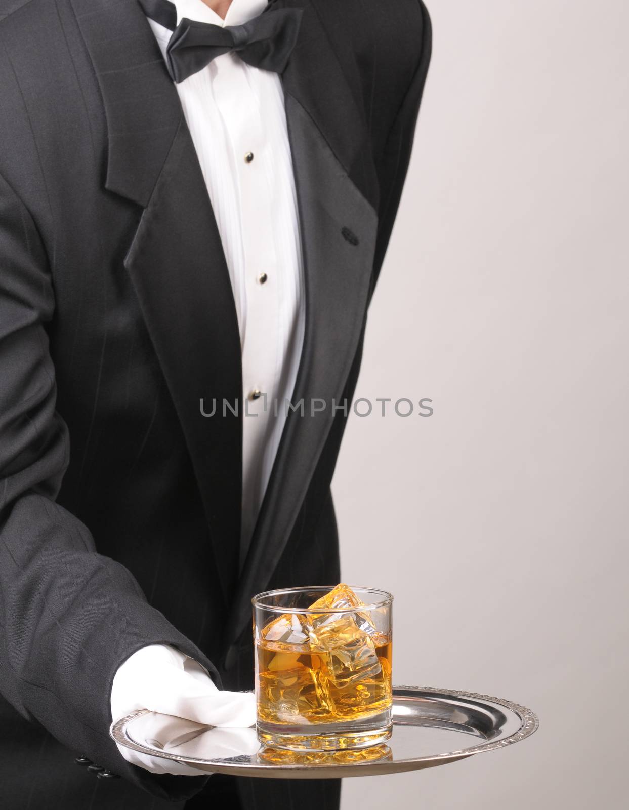 Waiter in tuxedo Presenting Cocktail on silver tray vertical format torso only