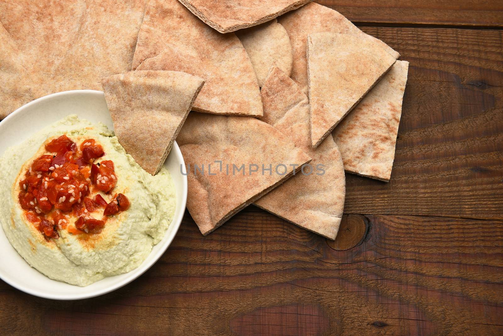 Pita bread wedges and edamame hummus on a rustic wooden table. Horizontal format from a high angle.