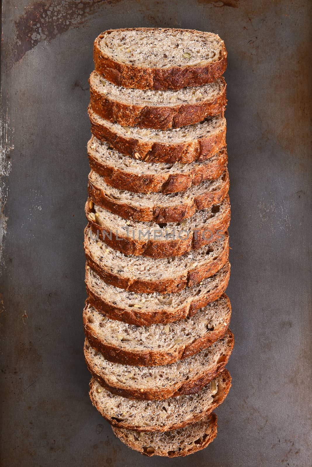 Top view of a sliced loaf of multi-grain bread on a baking sheet.