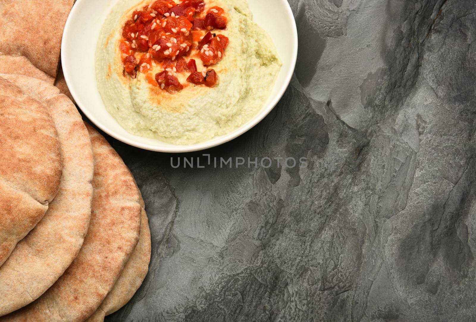 Pita bread and edamame hummus on a slate table with copy space.