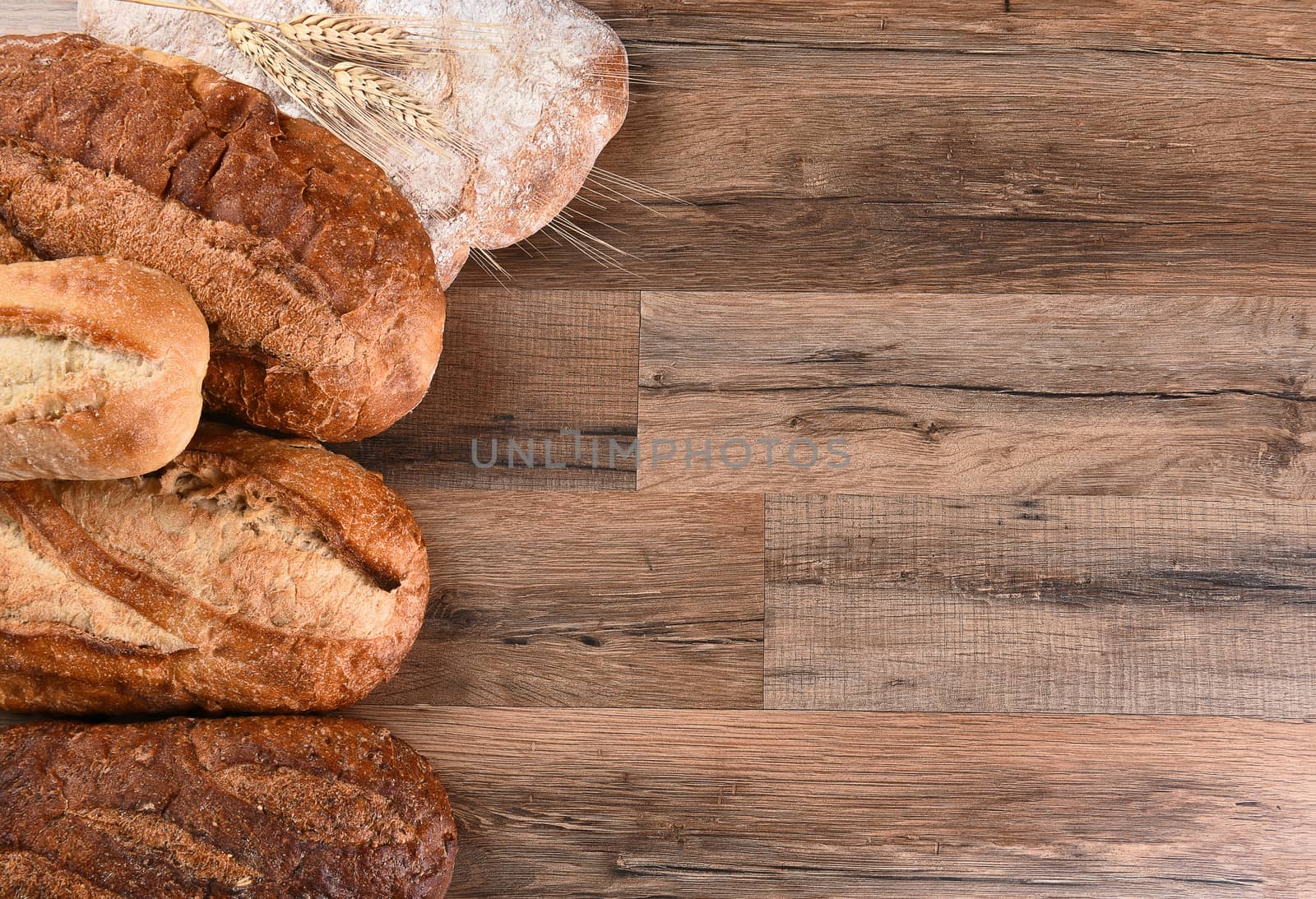Five different loaves of bread on a wood table with copy space. Horizontal format.