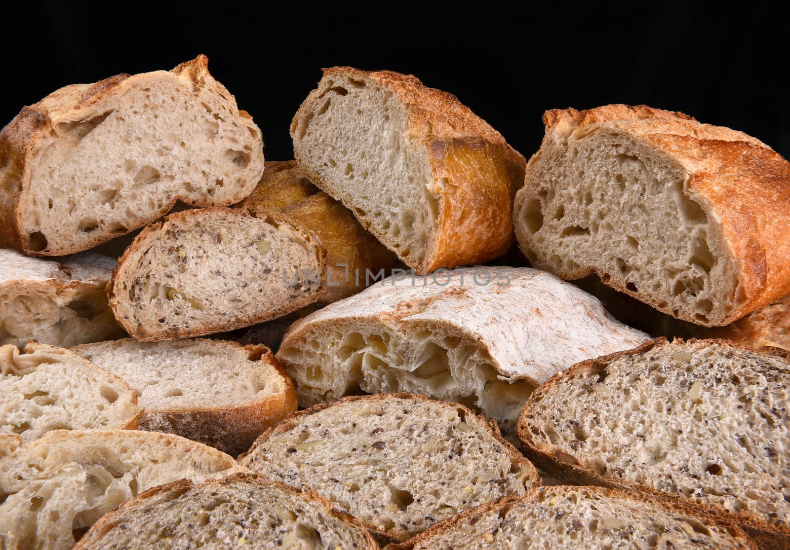 A variety of fresh baked loaves of bread, the loaves are cut in half and sliced. 