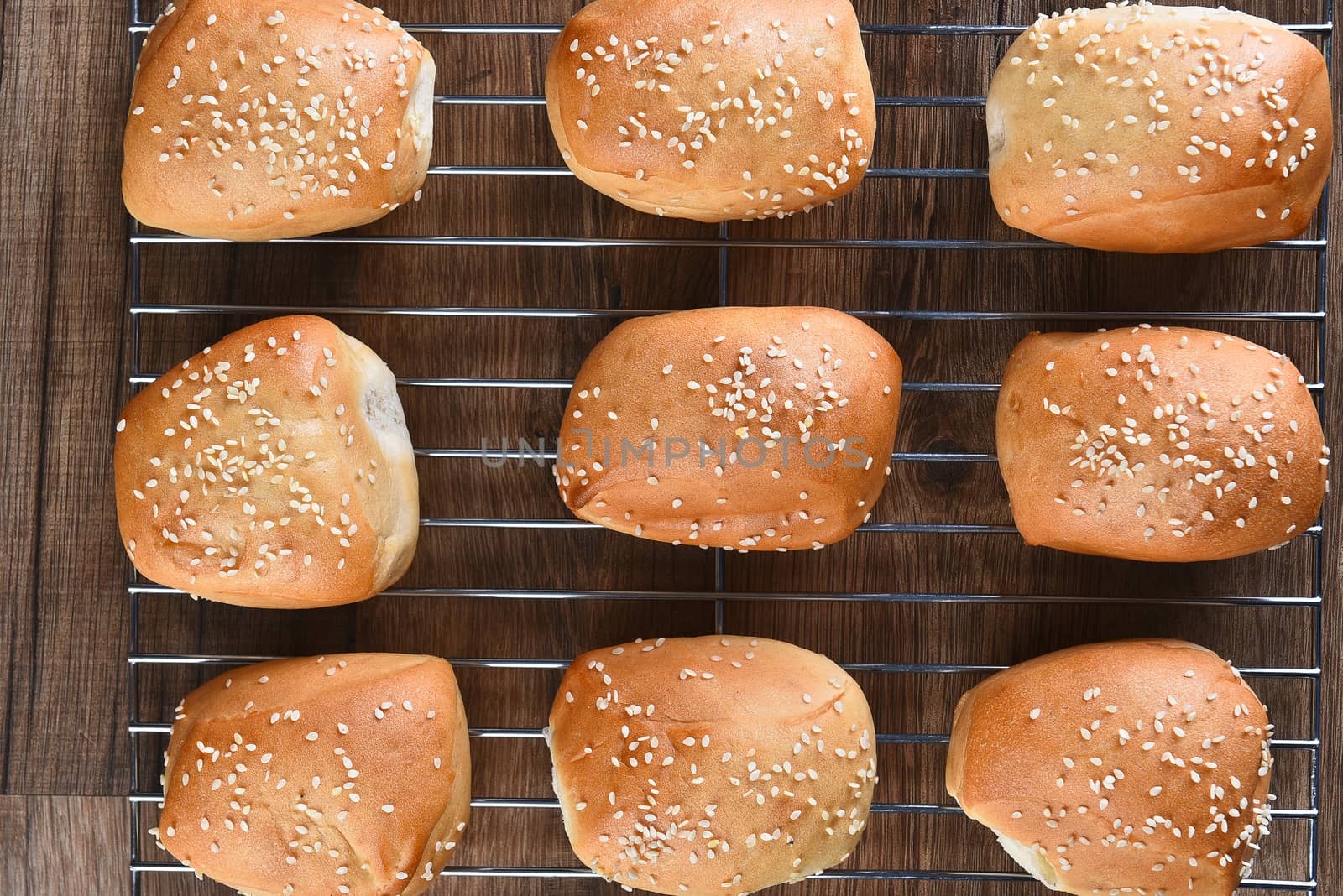 Closeup top view of fresh baked sesame seed dinner rolls on a cooling rack.