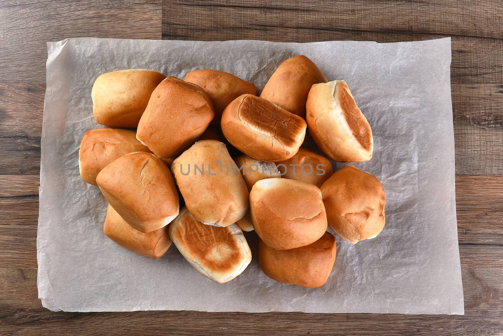 Pile of fresh baked dinner rolls on a sheet of parchment paper. Top view in horizontal format.