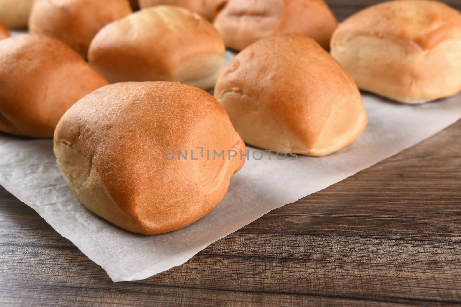 Closeup of fresh baked dinner rolls on a sheet of parchment paper.