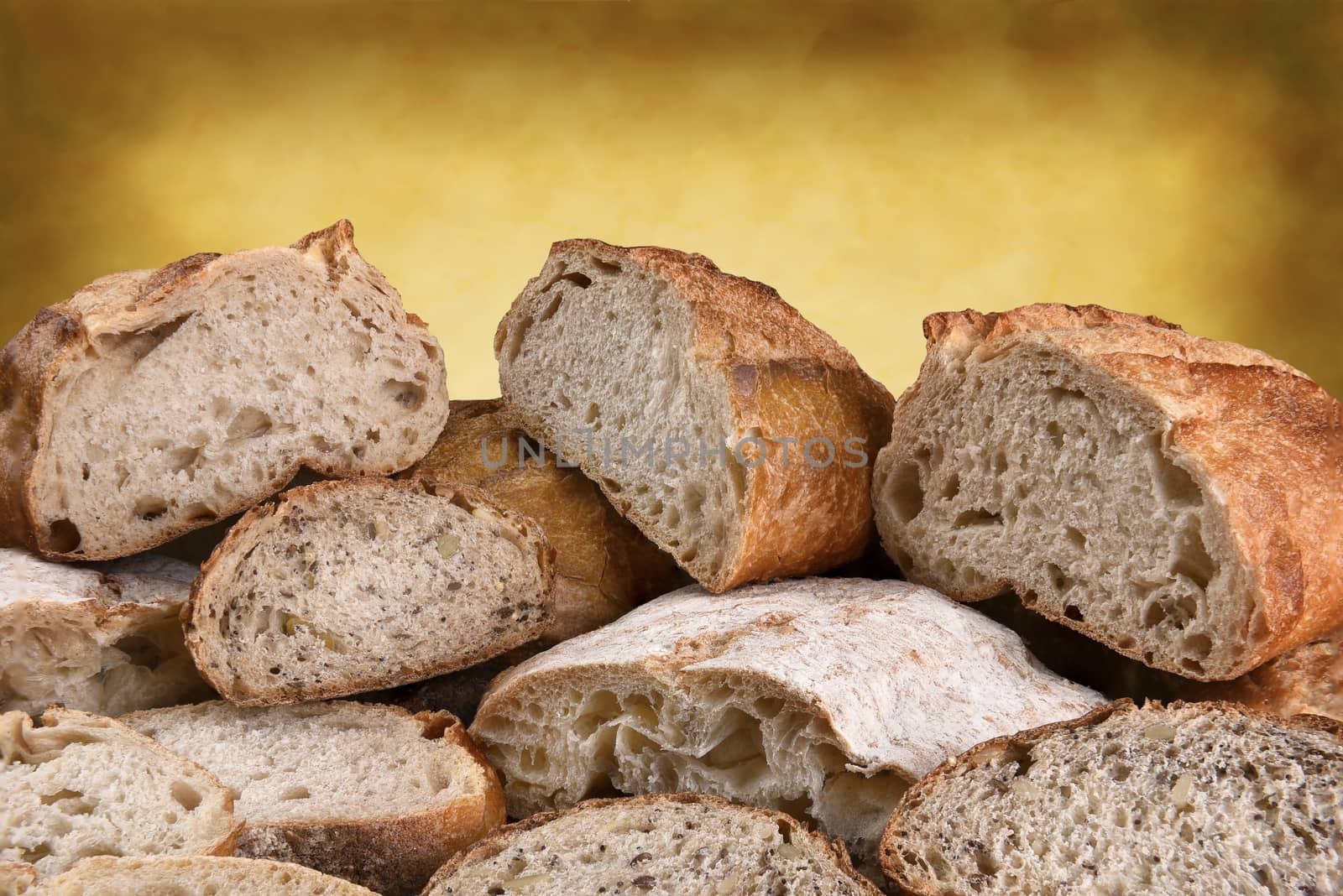 A variety of fresh baked bread on a warm background, the loaves are cut in half and sliced. 