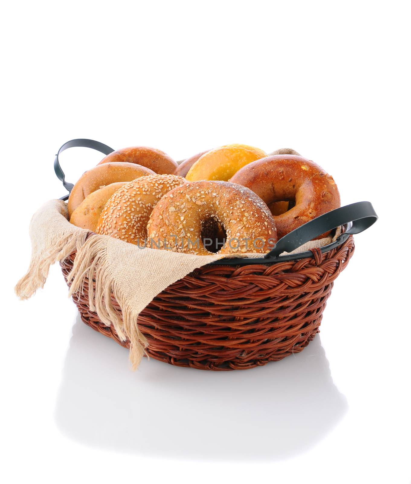 A basket of assorted bagels on a white surface with reflection. A variety of bagels including: egg, sesame, multi-grain, onion, and cinnamon.