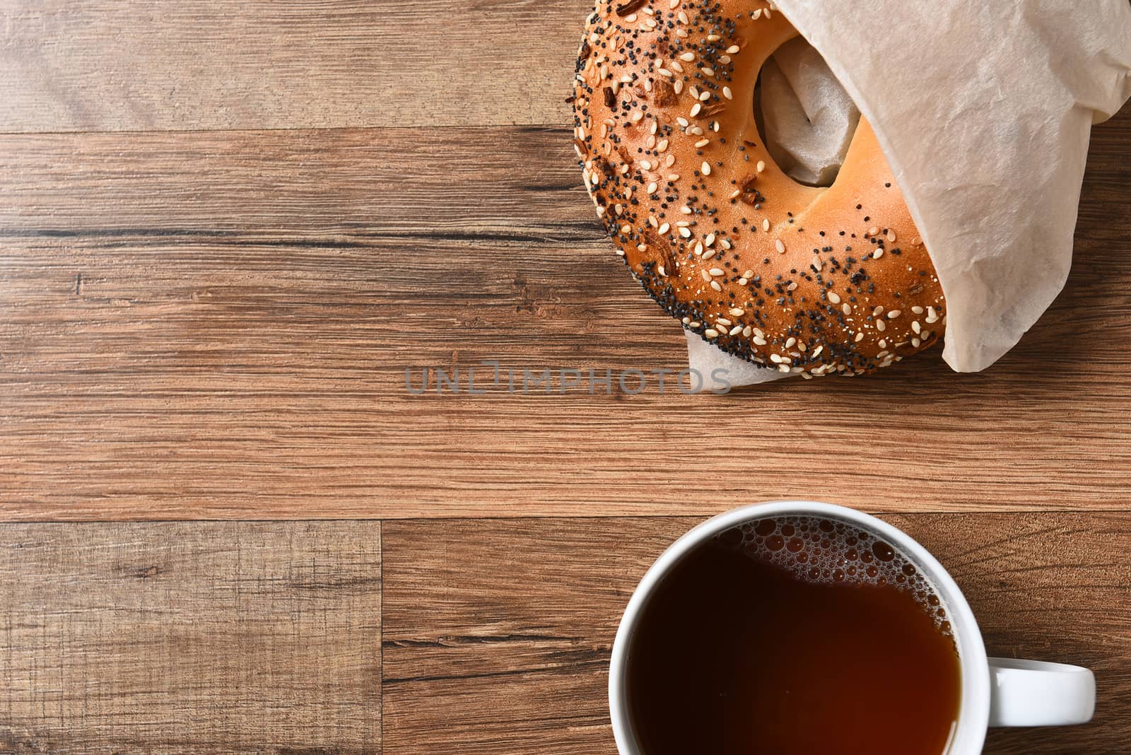 Fresh bagel and hot cup of coffee on a rustic wood table with copy space.