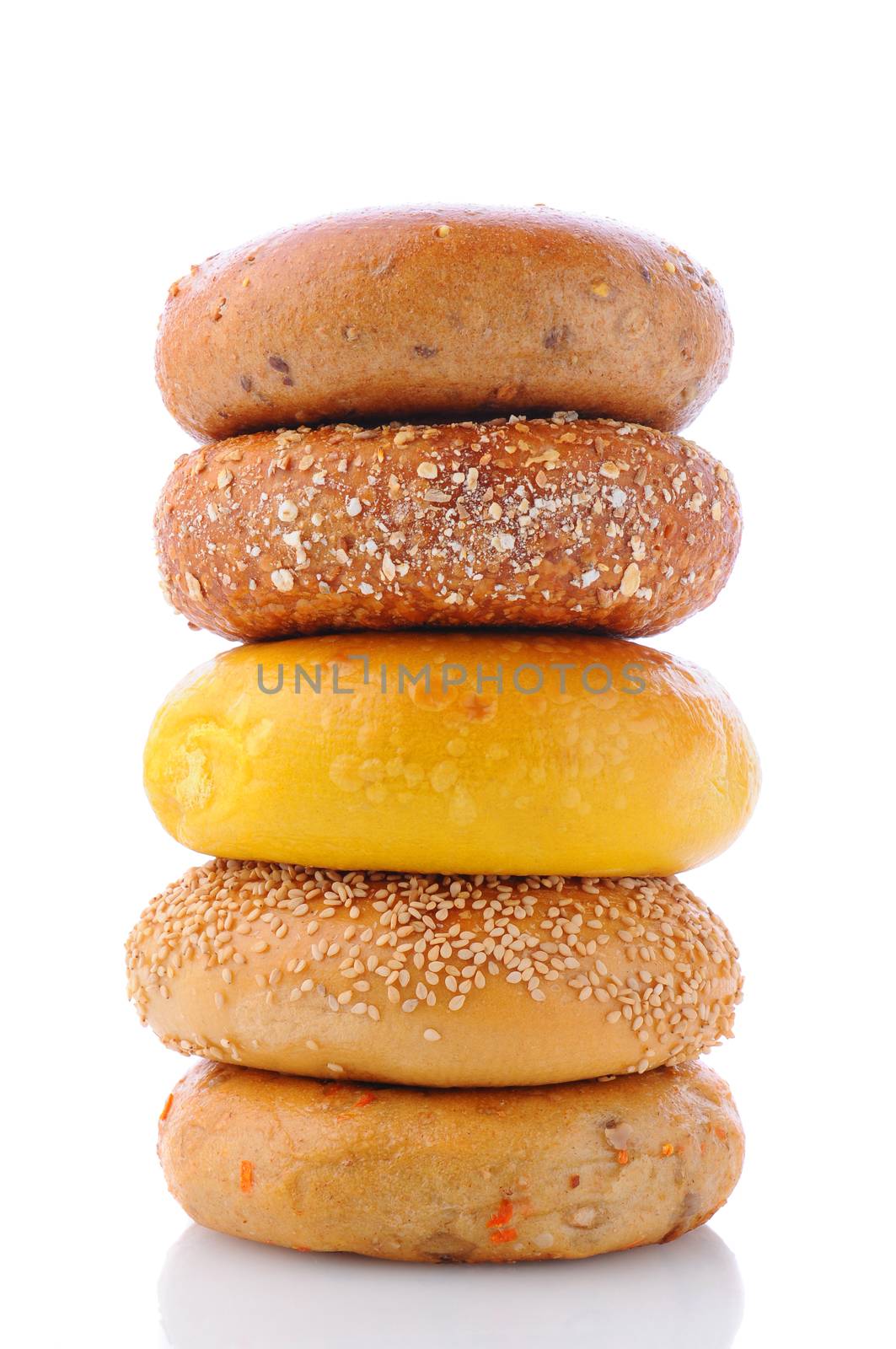 A stack of five different bagels on a white background with reflection. Bagels include: sesame seed, cinnamon raisin, multi grain, egg, and everything.