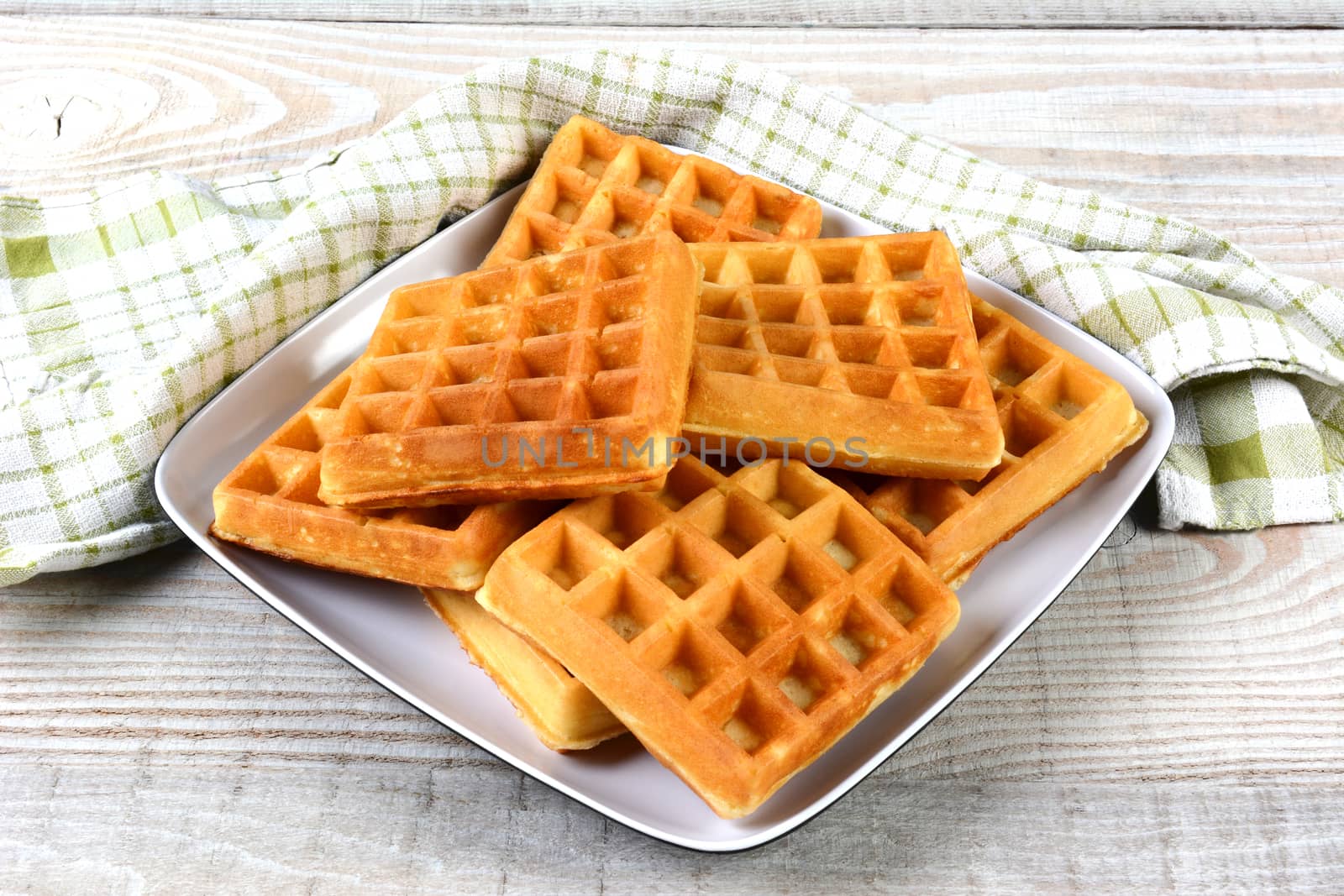 A plate of fresh made waffles on a rustic farmhouse style table. 