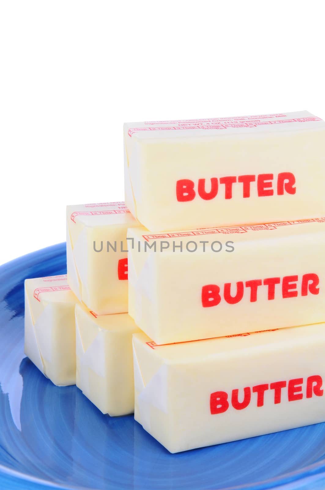 Closeup of sticks of wrapped butter on a blue plate. Vertical format over a white background.