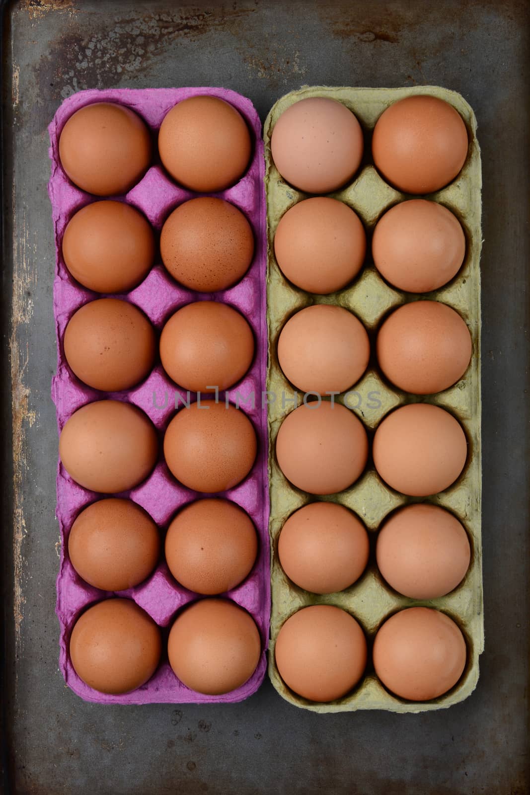 High angle shot of two one dozen cartons of organic brown eggs on a well used cooking surface.. Vertical format.