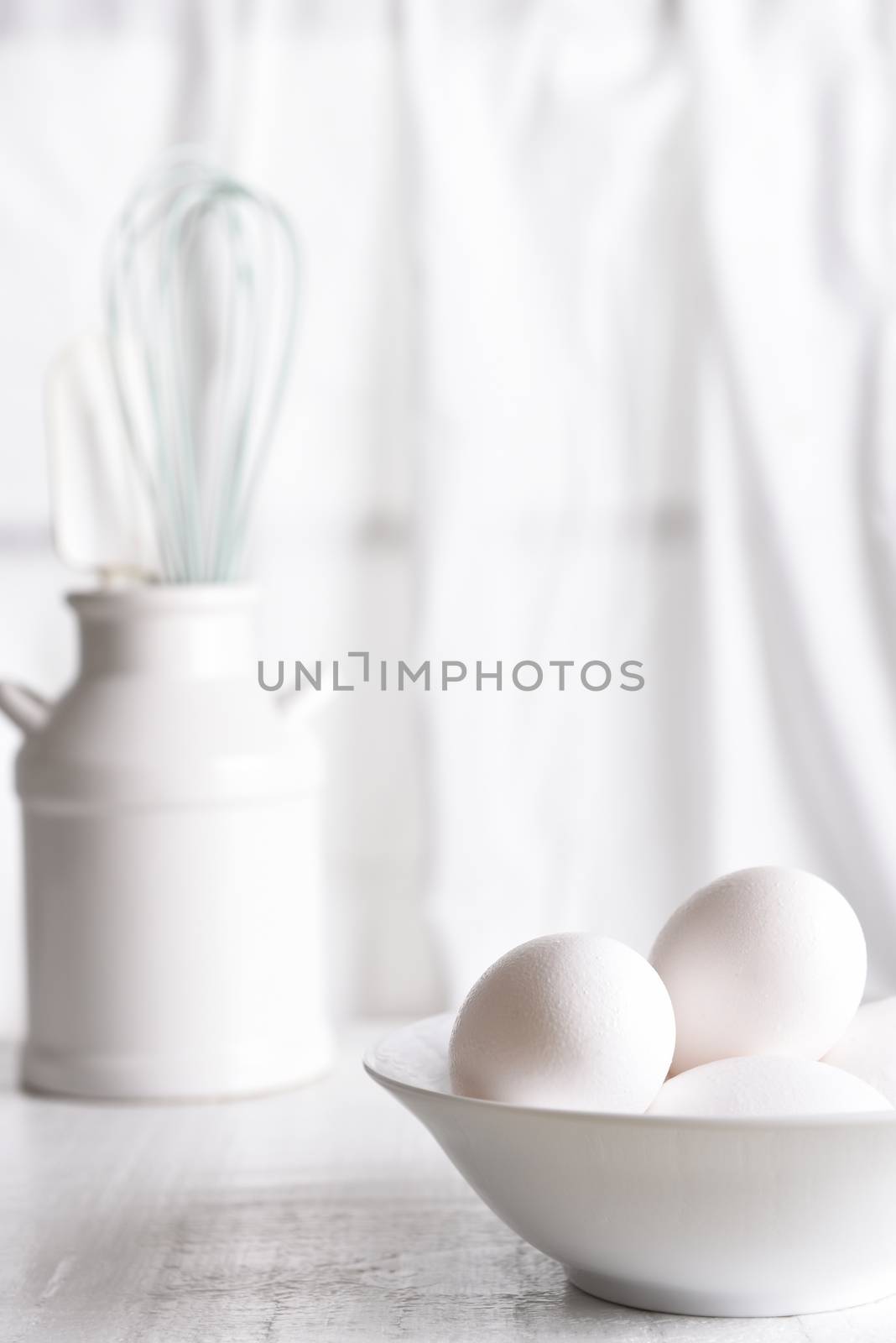 High Key Egg Still Life: Fresh eggs in a white bowl in front of a window with white curtains. Vertical orientation.