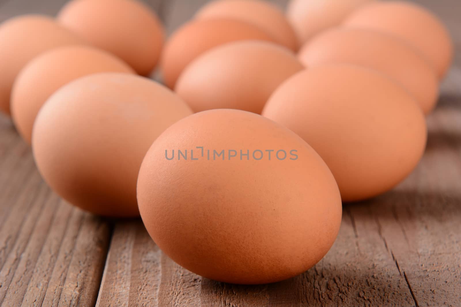 Closeup of a group of brown eggs on a rustic wooden table. Horizontal format with shallow depth of field.