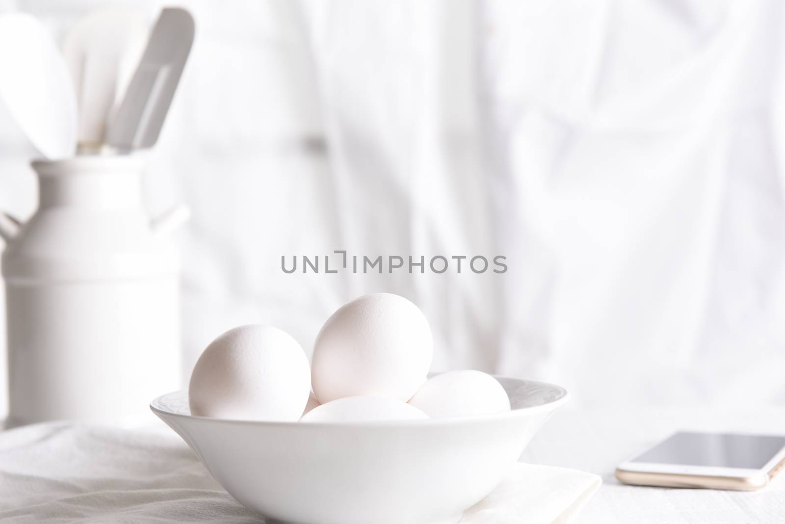 High Key Egg Still Life: Fresh eggs in a white bowl in front of a window with white curtains. Horizontal orientation.