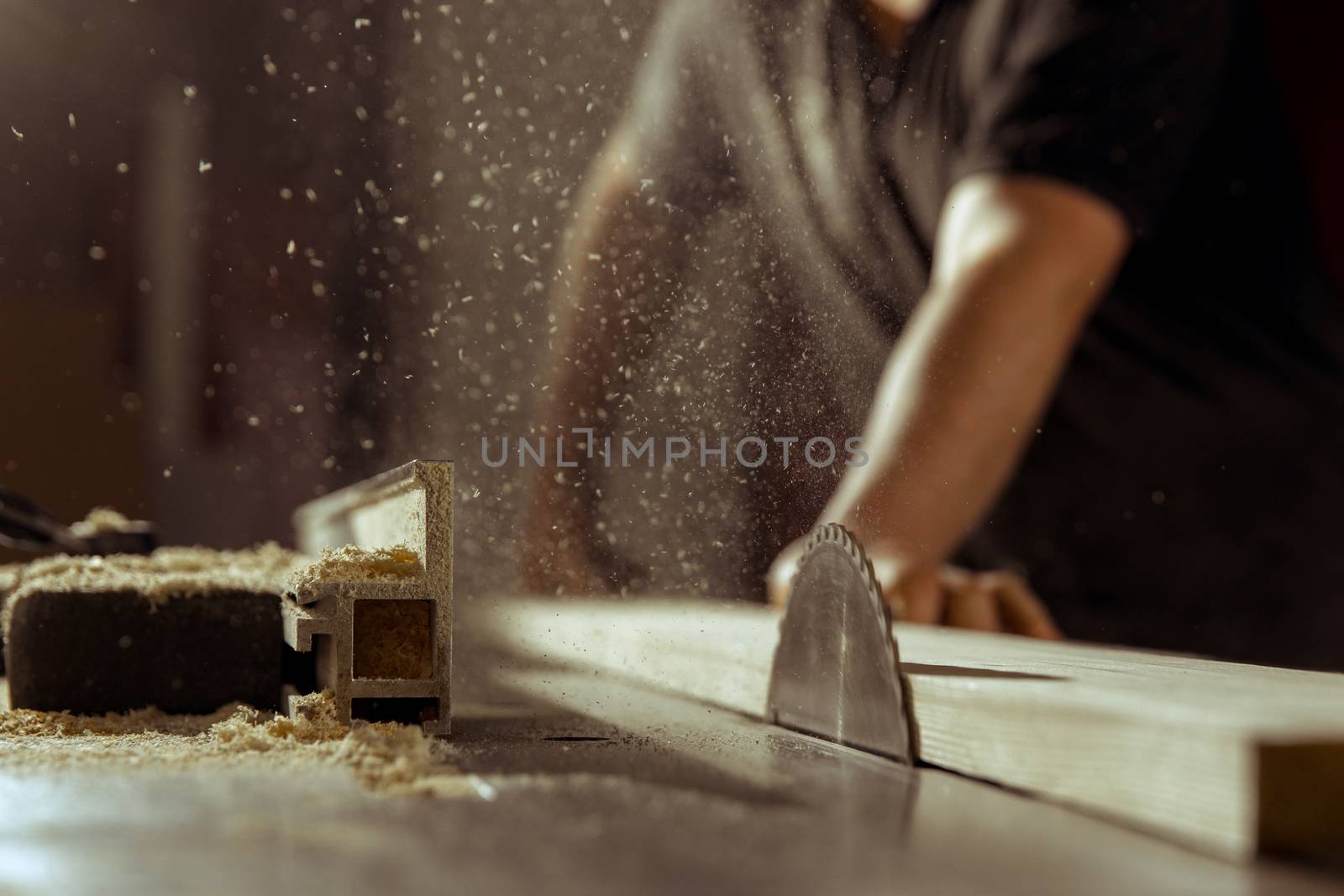 A man cuts wood on a circular saw in a joinery.