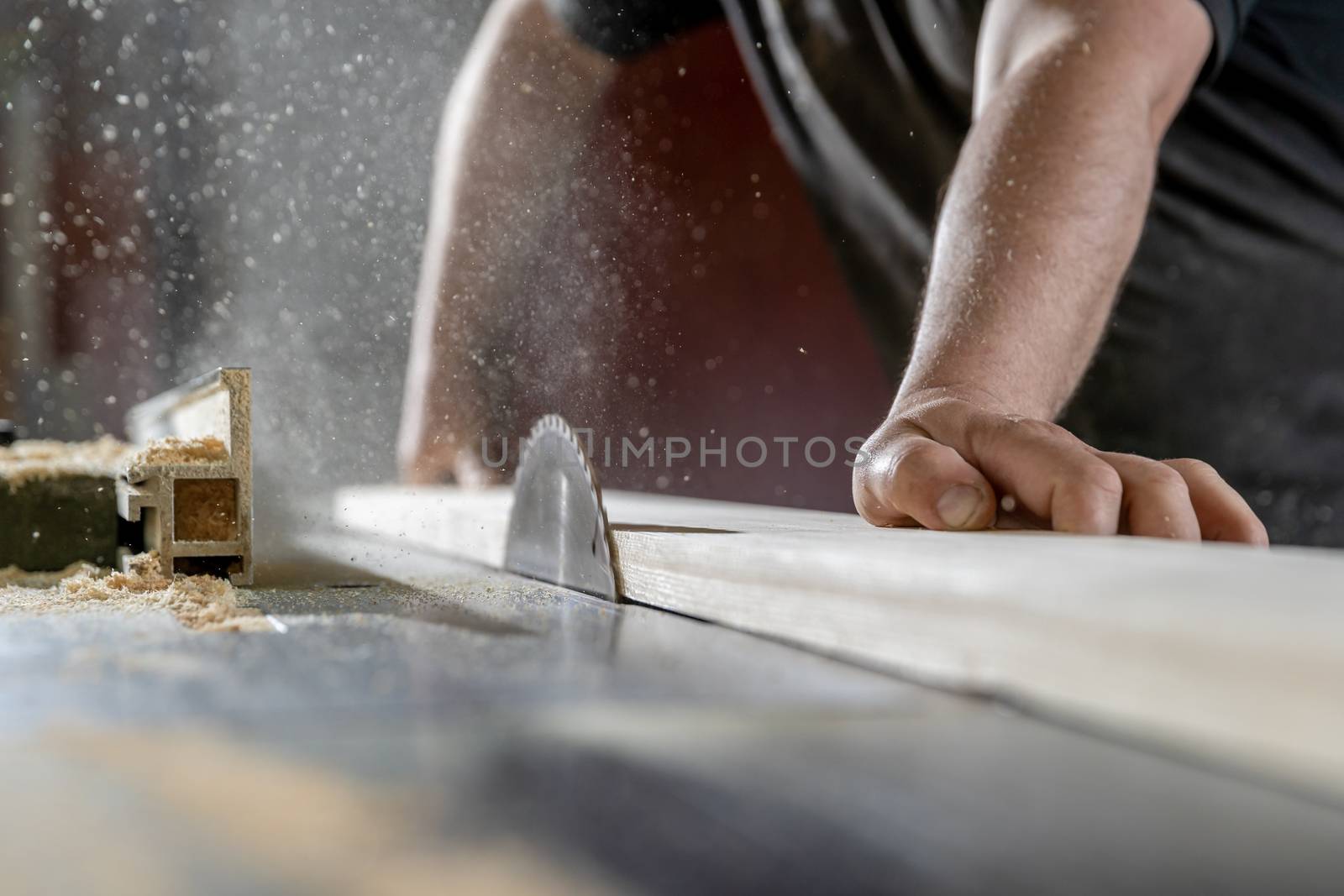 A man cuts wood on a circular saw in a joinery.