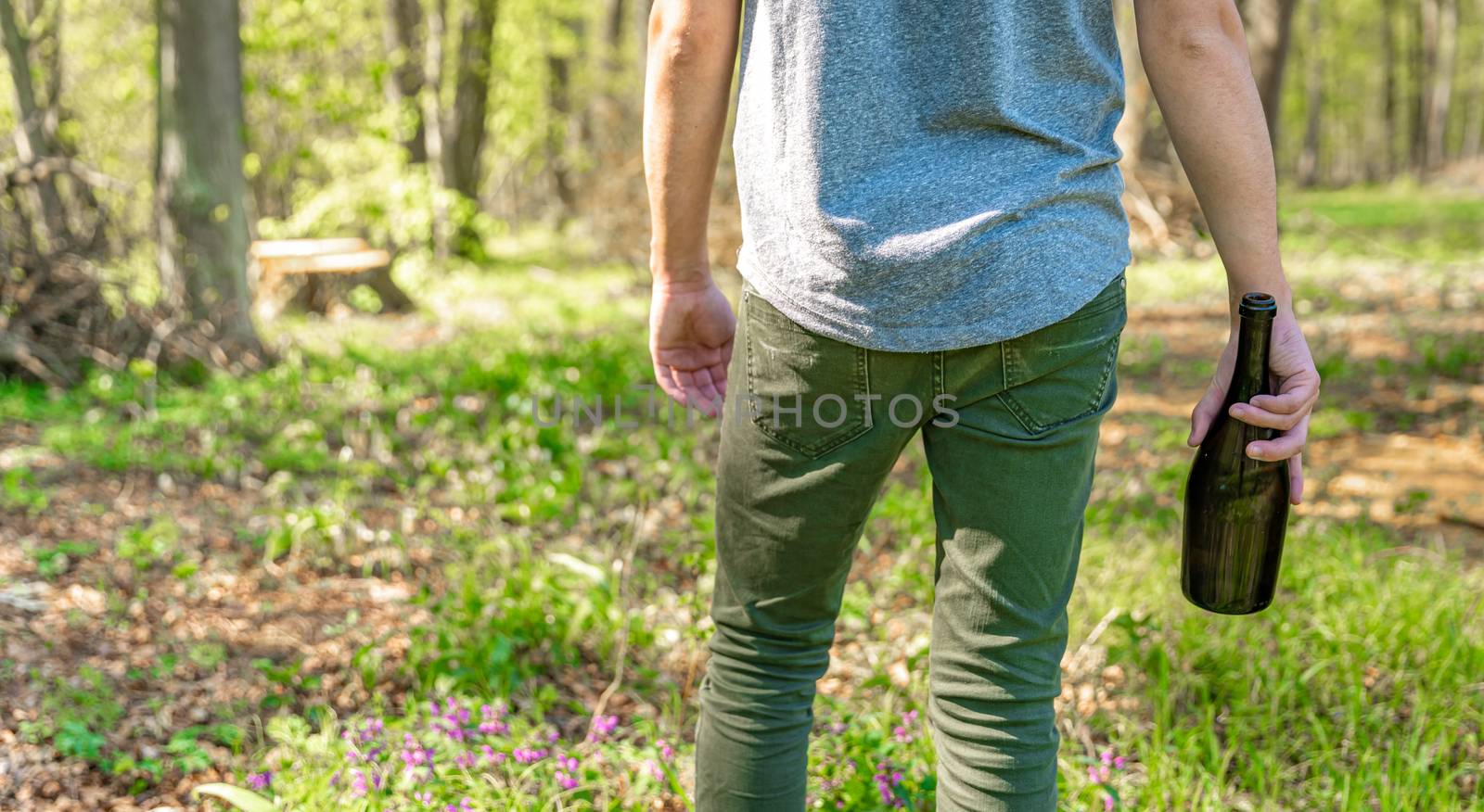 man with a bottle of alcohol in the woods. Solving the problem of drunkenness and loneliness.