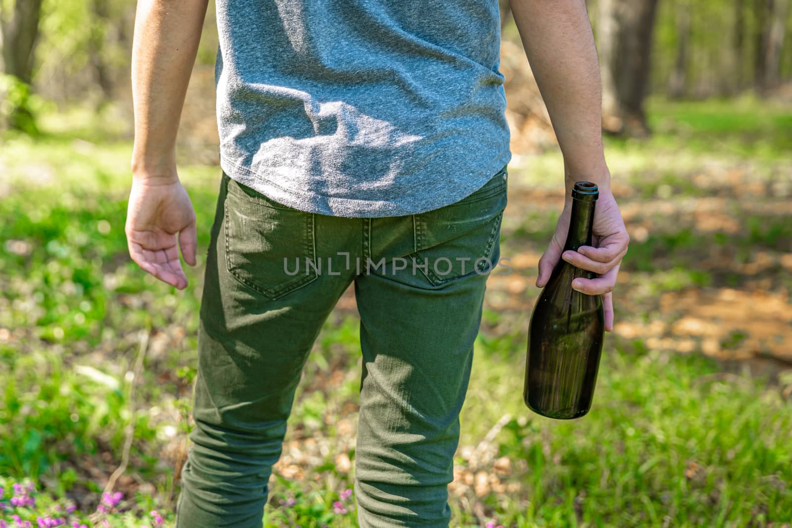 drunk man with a bottle of alcohol in hand in nature.