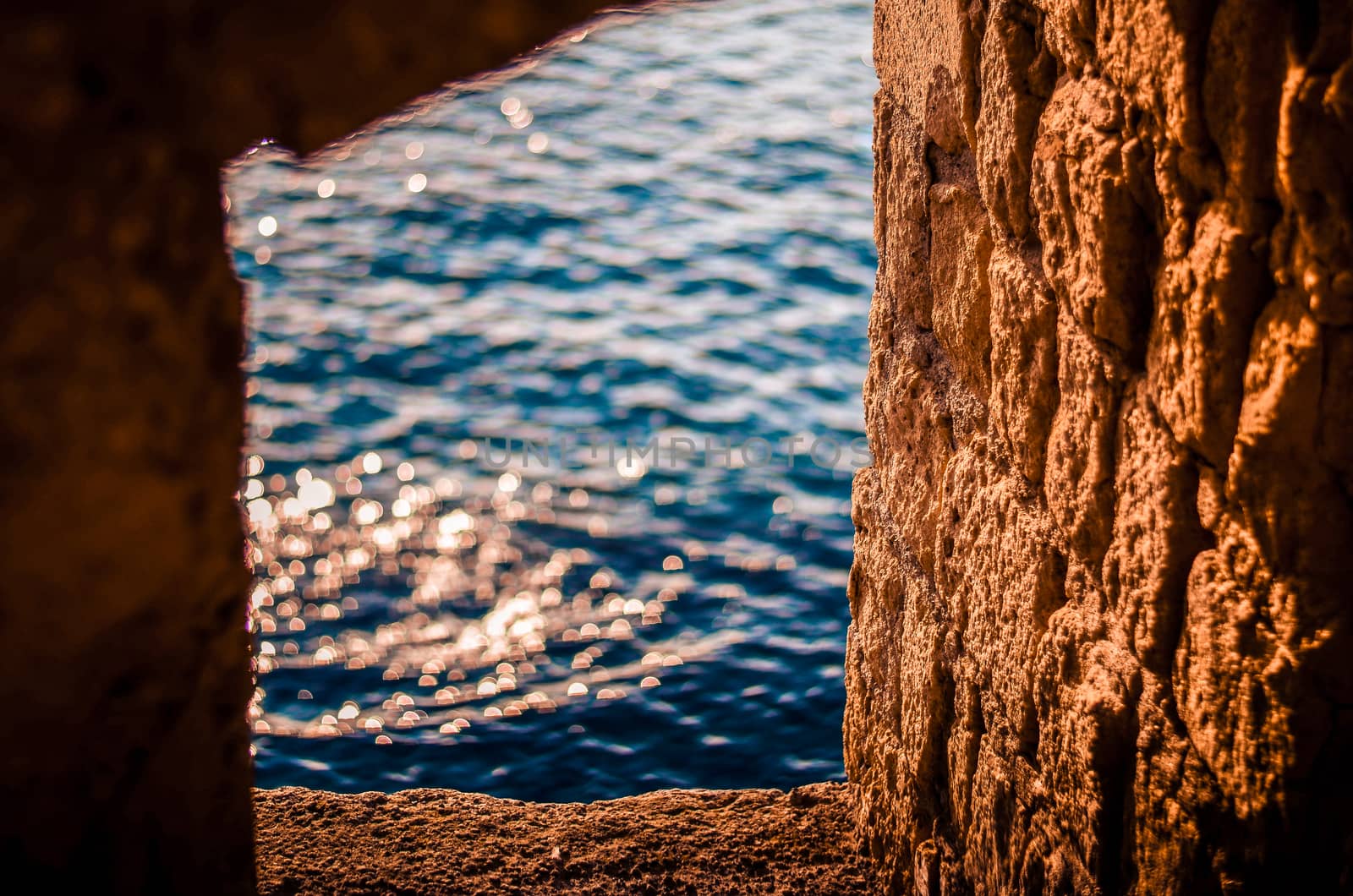 Castle ruins. Window in the old stone wall. Reflection of the sun's rays in the sea water