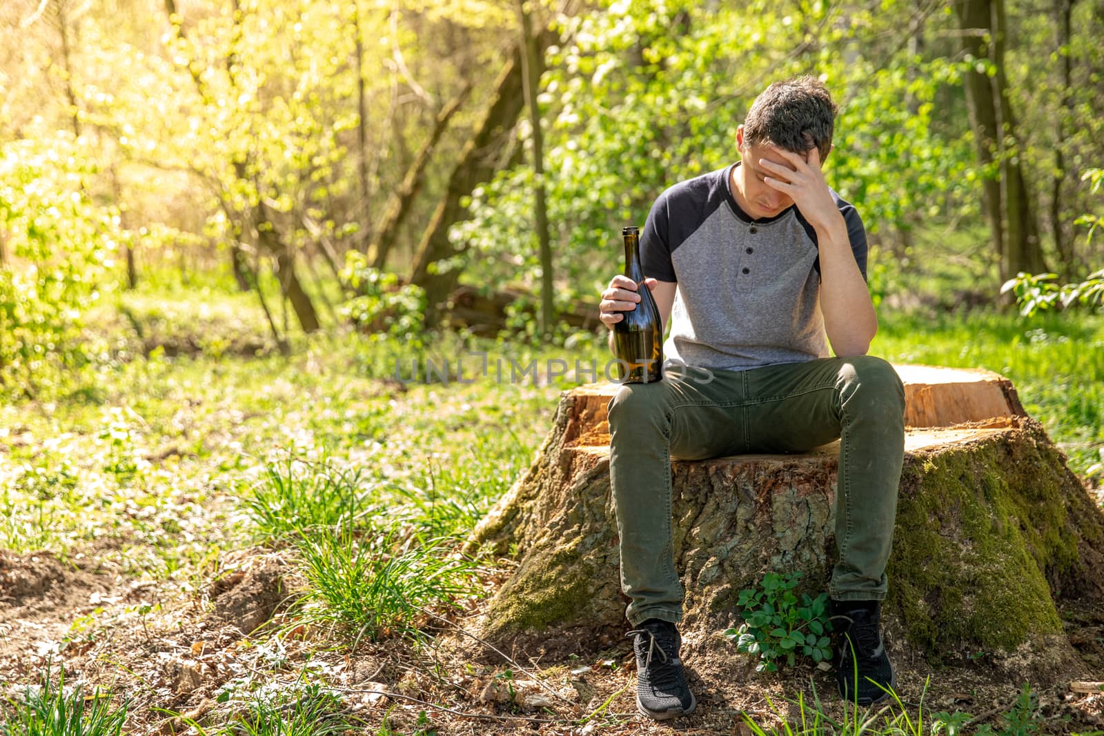 alcohol as a solution to a problem, a worried man with a bottle in his hand thinking about worries in the woods