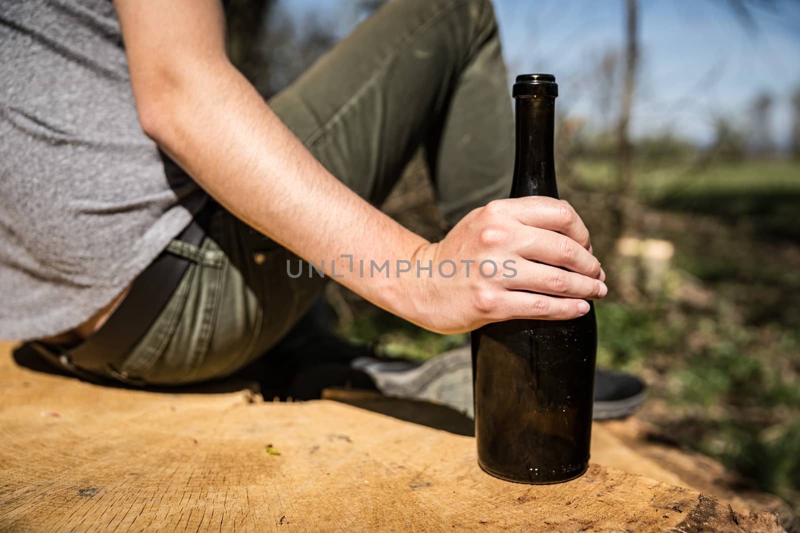 a bottle of wine in a man's hand, drinking alcohol in nature.