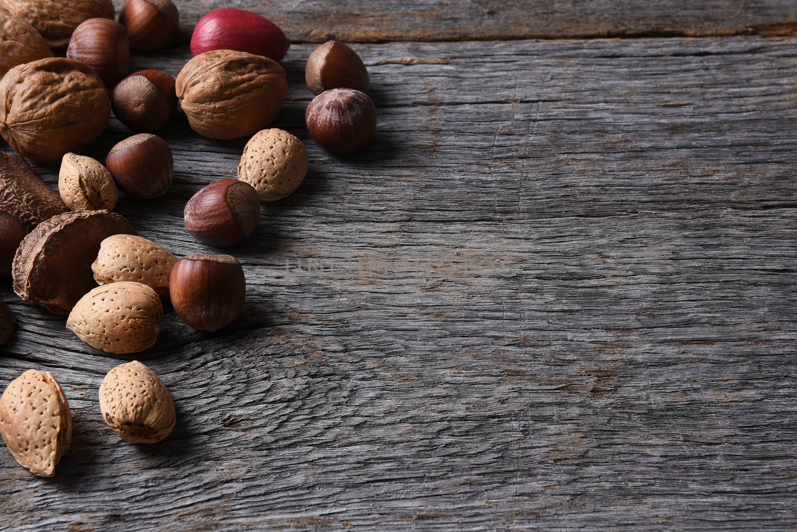 Mixed nuts on a rustic wood table with copy space, Walnuts, Pecans, Hazelnuts, Brazil Nuts and Almonds make up the array.