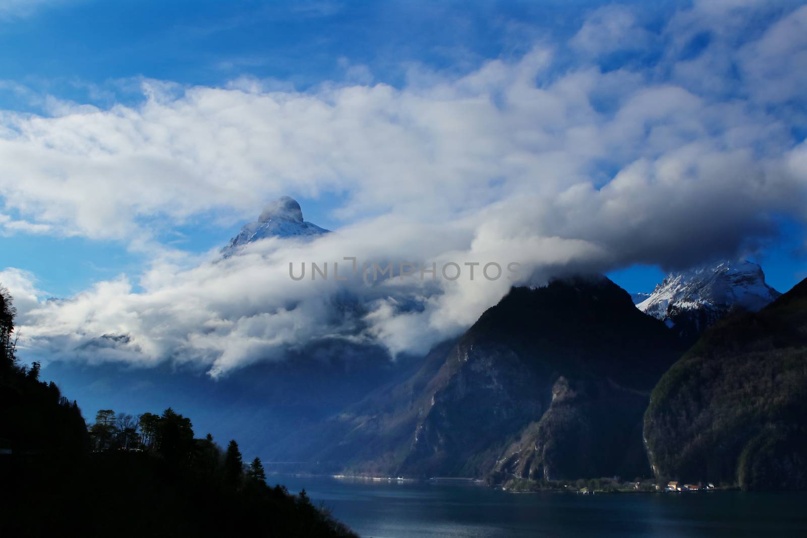 clouds and mountains with a lake in foreground near Brunnen by PeterHofstetter