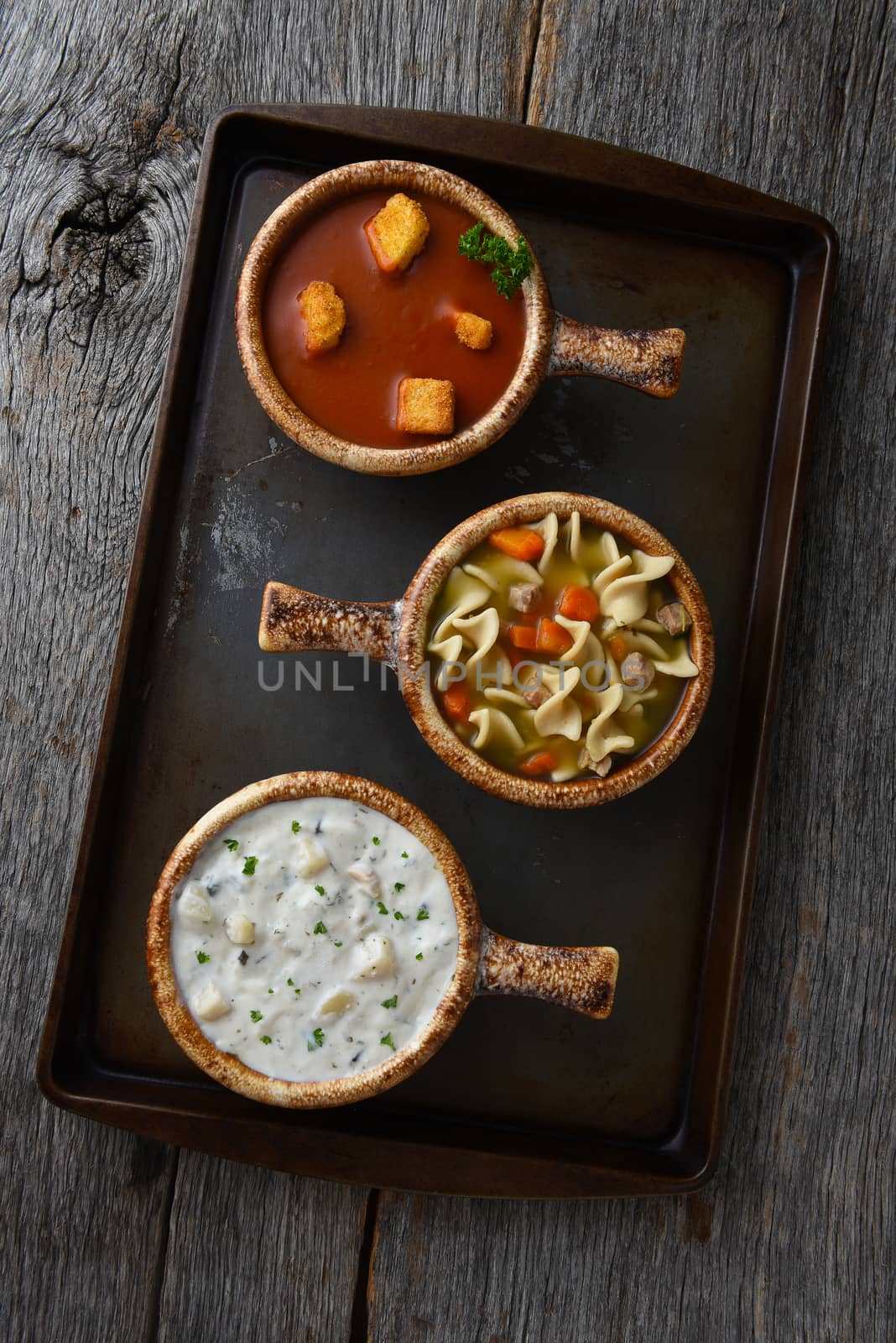 Overhead view of three different bowls of soup on a baking sheet by sCukrov