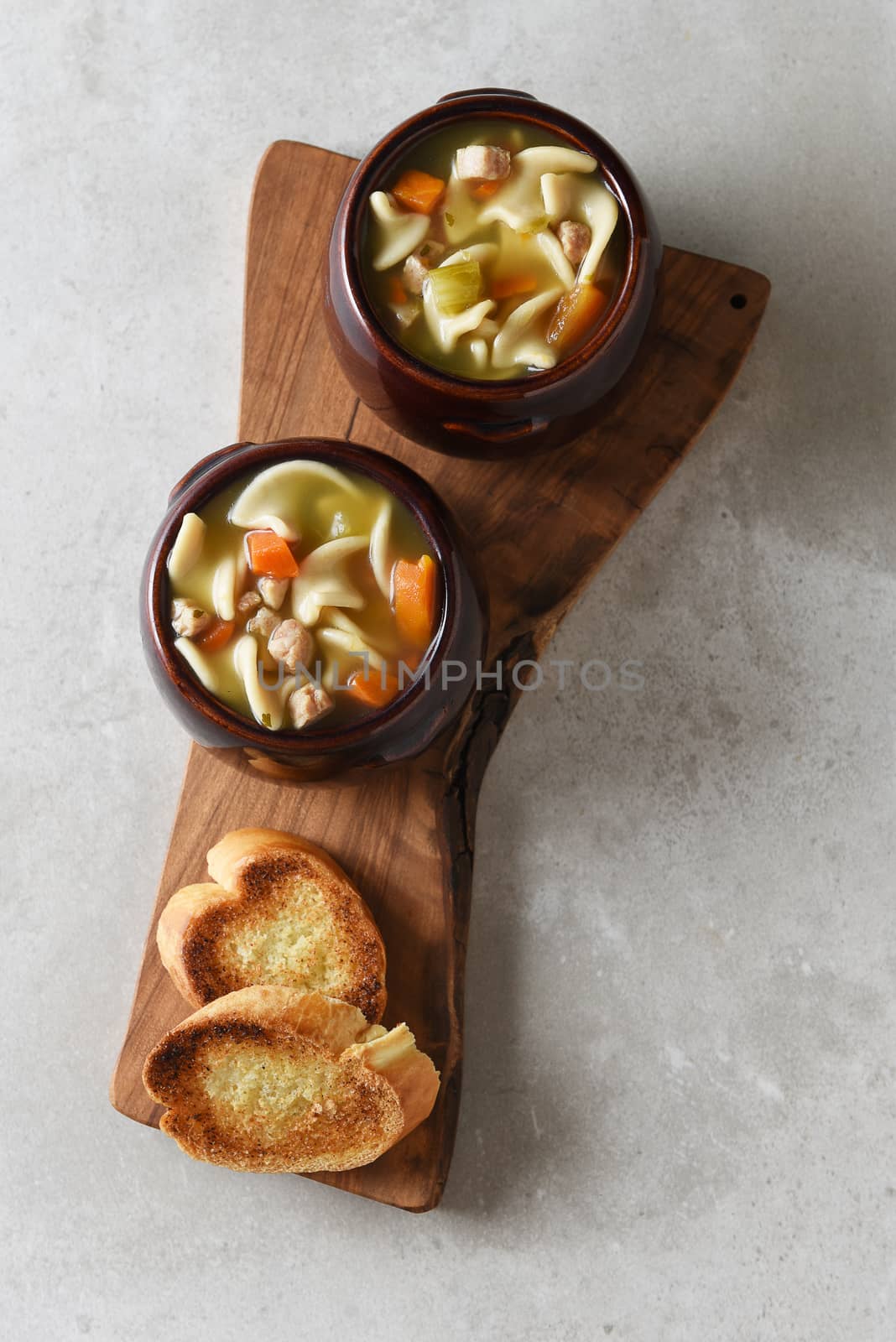 Two crock bowls of fresh homemade Chicken Noodle Soup on a cutti by sCukrov