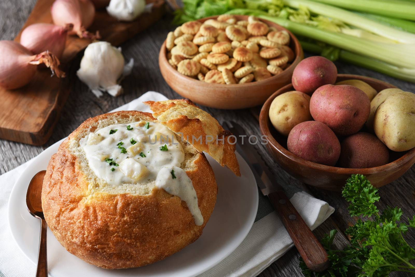 New England Clam Chowder: A bread bowl full of fresh homemade soup with crackers and ingredients.