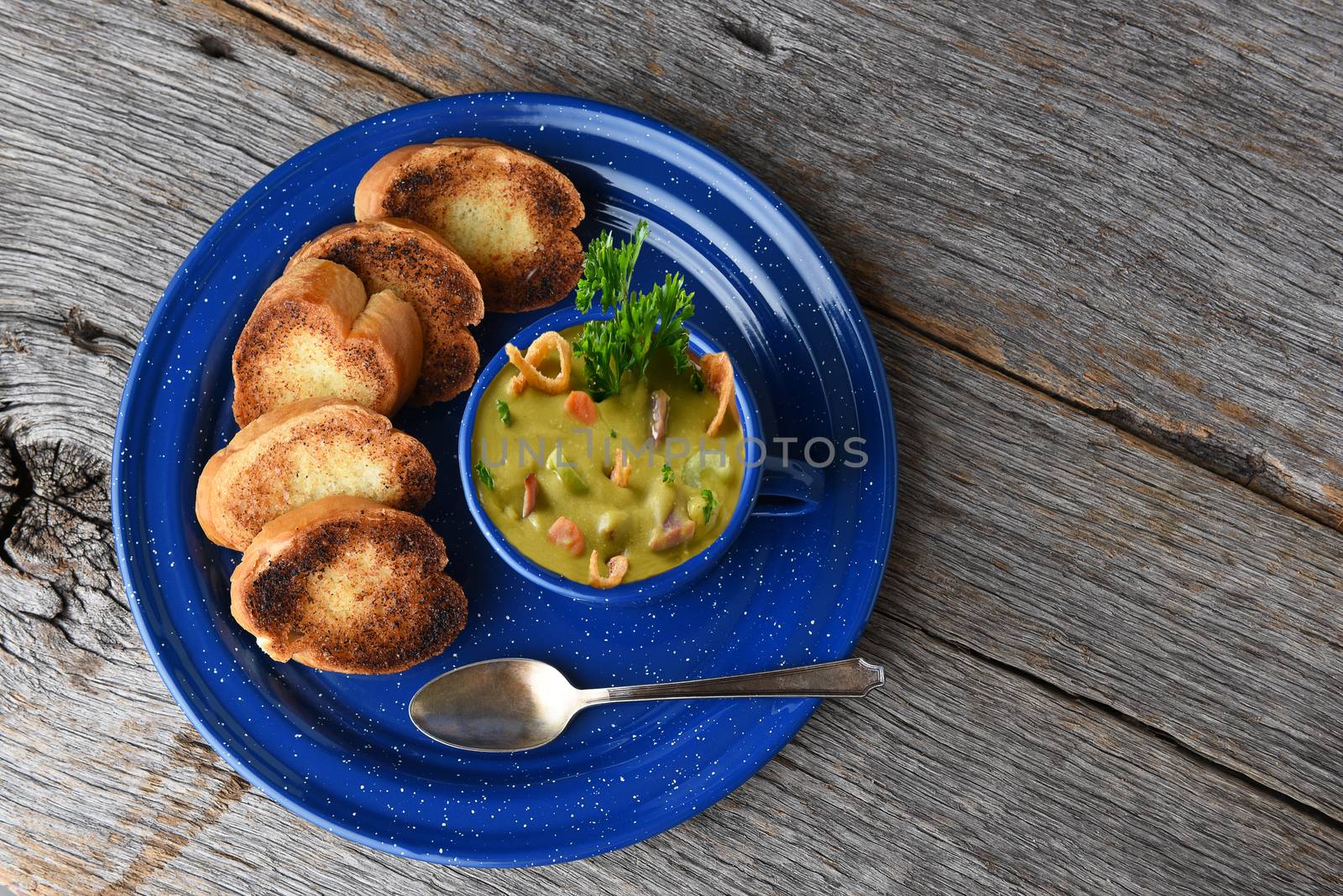 High angle shot of a mug of fresh homemade Split Pea soup with garlic toast on a rustic wood table with copy space.