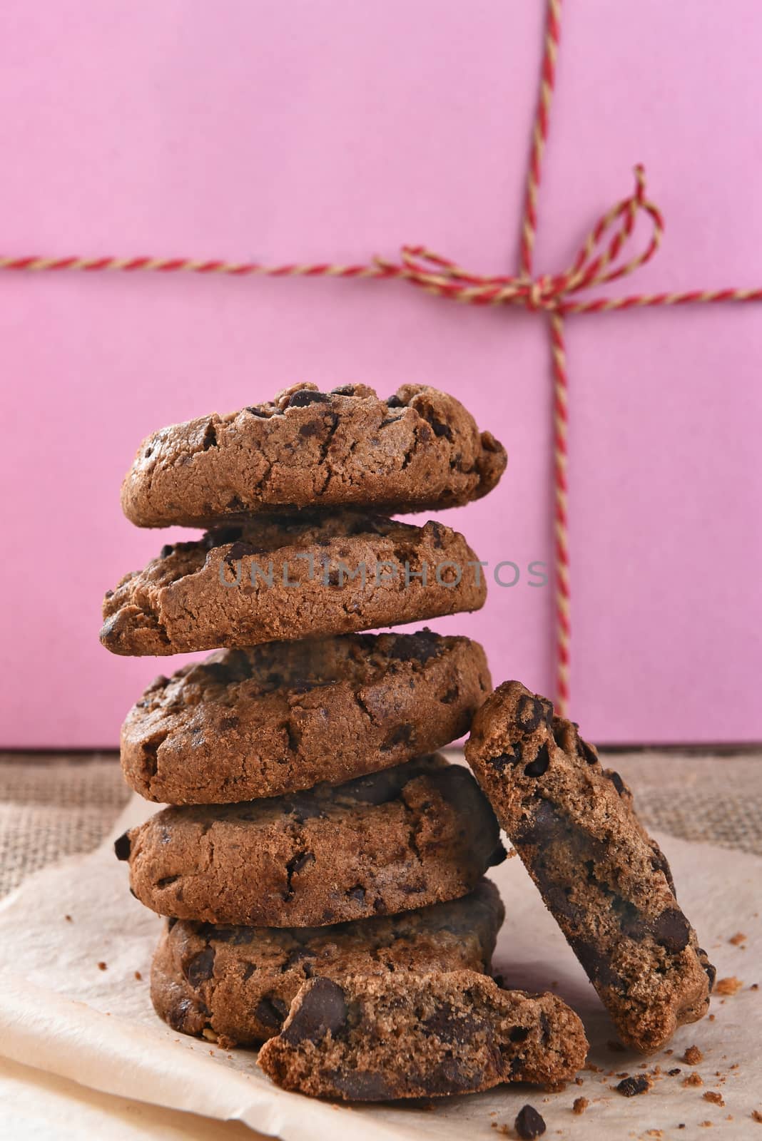 Closeup of a stack of chocolate chocolate chip cookies in front of a pink bakery box.