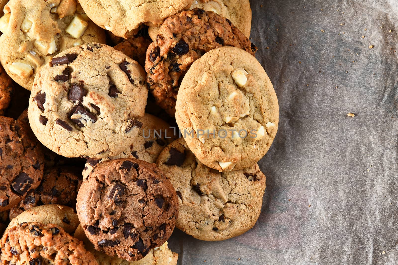 Closeup of a group of assorted cookies. Chocolate chip, oatmeal raisin, white chocolate pn parchment paper with copy space